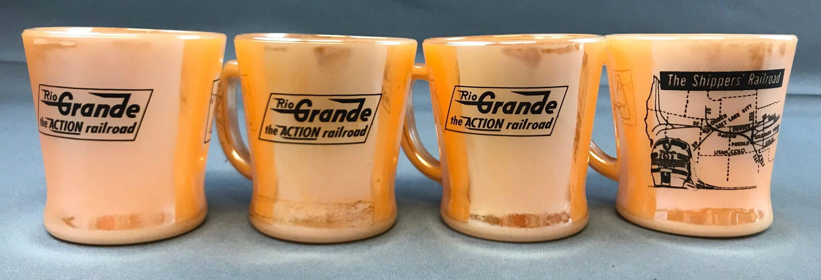 Group of 4 vintage Rio Grande railroad fire king mugs: Peach lusterware D handle mugs. Rio grande railroad logo on one side, map on other.