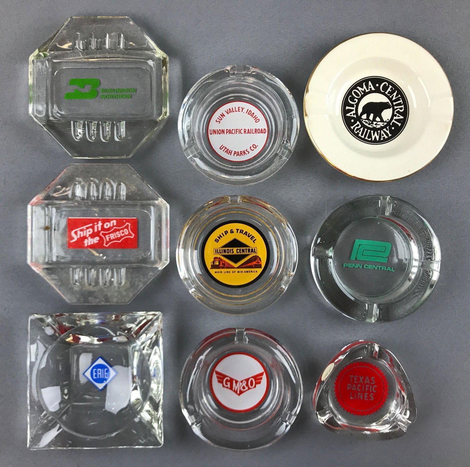 Group of 9 vintage railroad line glass ashtrays: Penn central, Frisco, Burlington Northern, Erie and more. Largest is 5x5 inches.