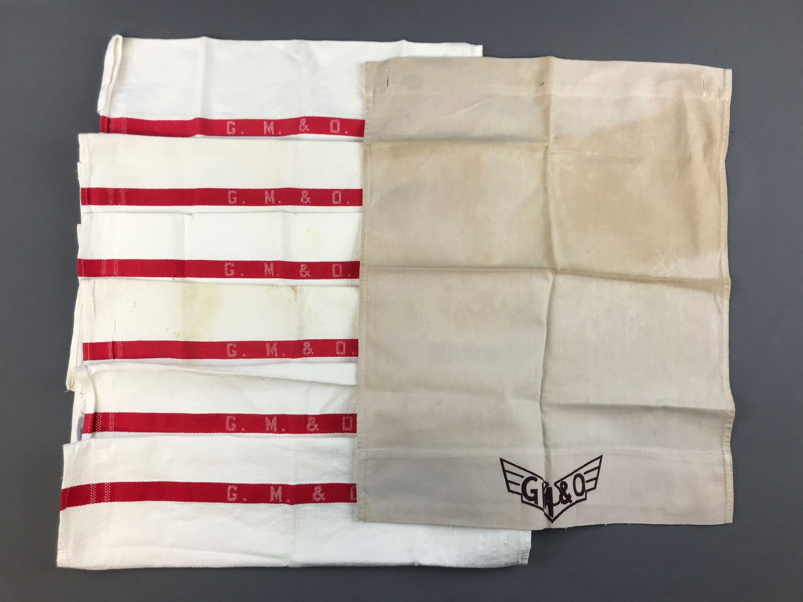 Group of 7 vintage GM and O railroad linens: 6 hand towels, one headrest cover. Some wear and stains. Cover is 15x19 inches