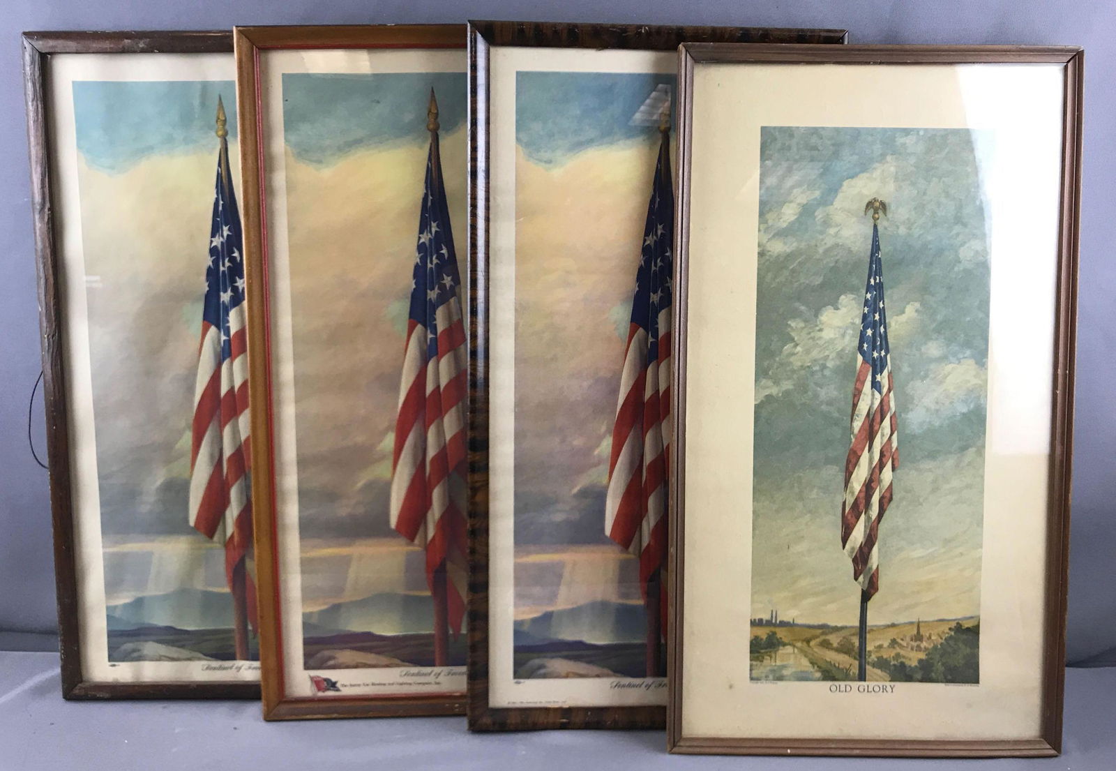 Group of 4 framed American flag prints: 3 sentinel of freedom, one old glory. Larger frames are 12x23 inches. Some damage/wear to all.