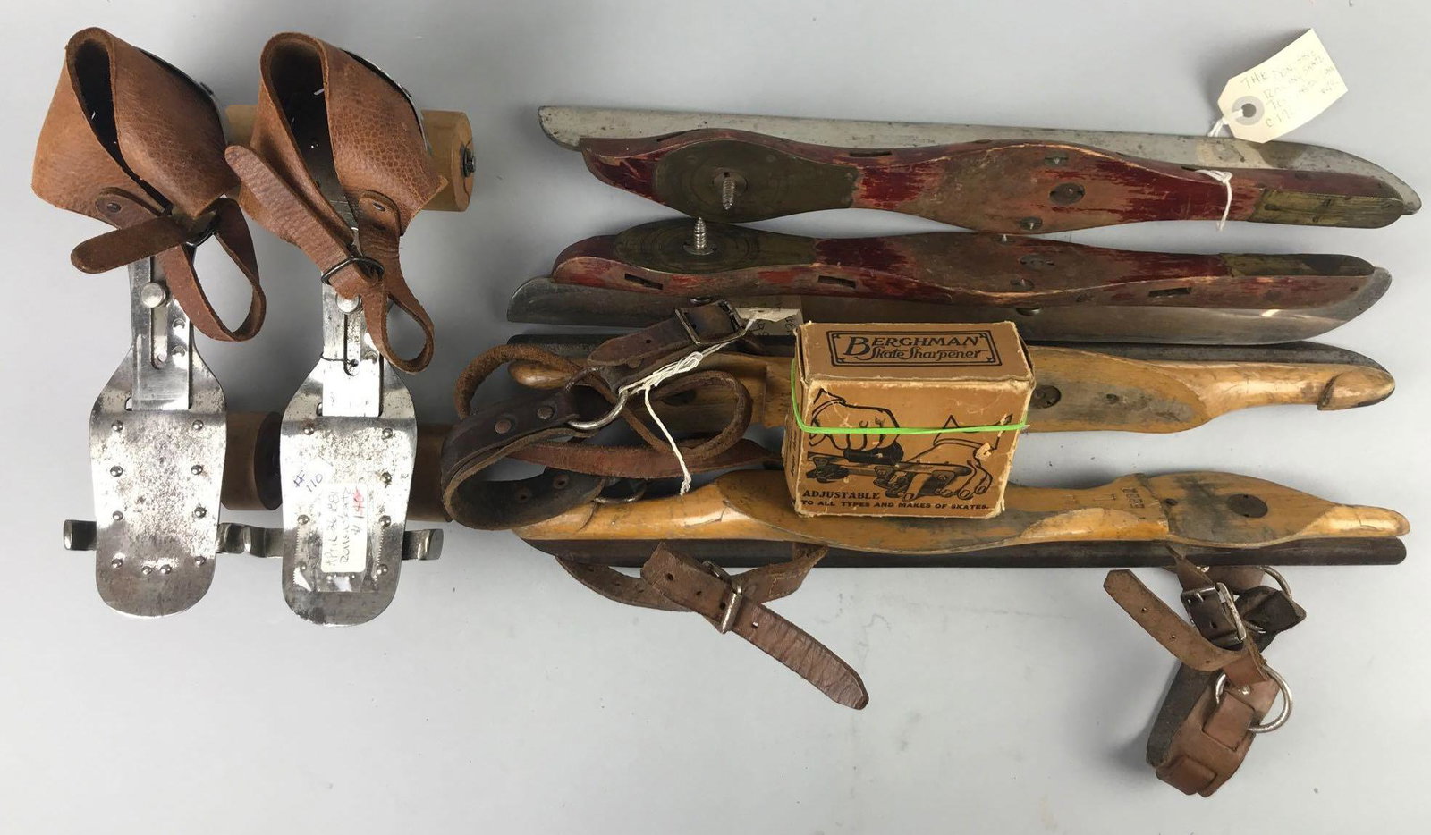 7 piece group antique skates and sharpener: 1 pair roller skates, 2 pairs ice skates, and sharpener in original box. Largest is 16.5 inches