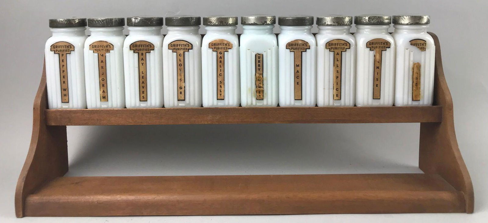 11 piece group vintage milk glass spice jars on wood: Griffiths Purified Spices. Rack measures 18.25x7 inches, jars are 4.25 inches.