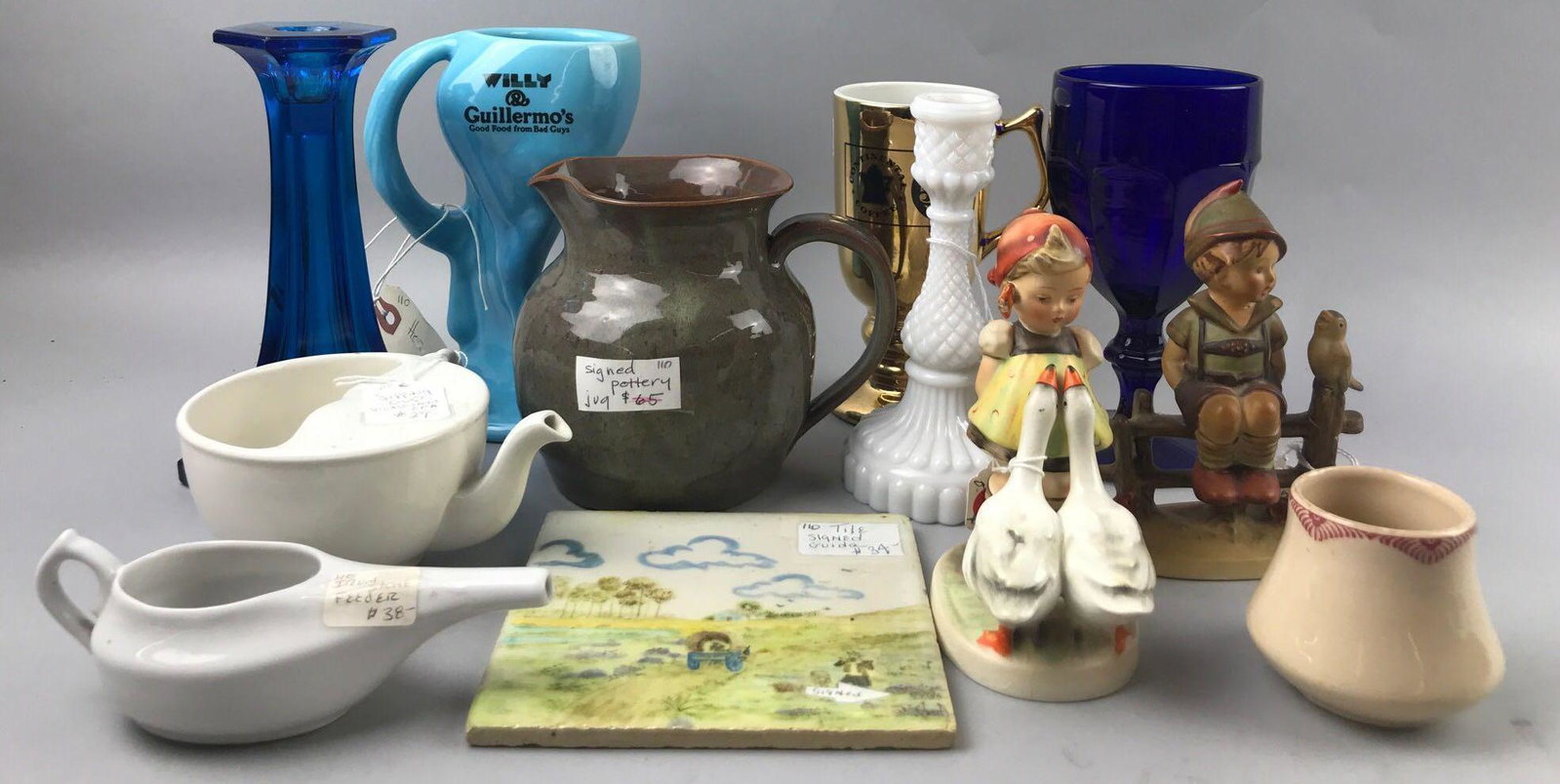 Group of 12 assorted ceramic and glass decorative: Includes Hummel figurines: Girl with Geese and Wayside Harmony. Crazing throughout both, boy has repair on neck. Largest is 7.5 inches. sorry no shipping on this lot.