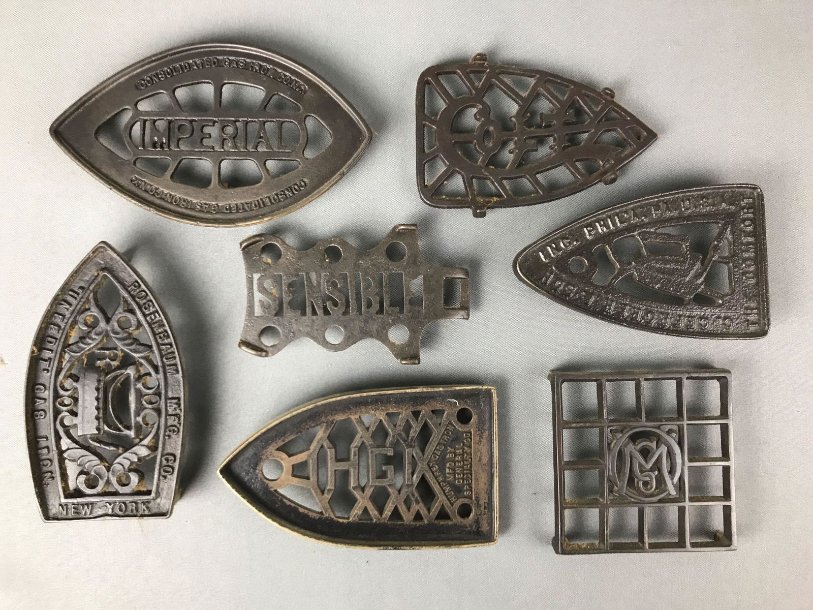 Group of 7 : Antique Cast Iron Trivets for Sad Irons -: Collection of cast iron trivets includes : Imperial; Colt;Rosenbaum; Humphrey Gas; O.M. Co.; and the "Comfort". Largest is 8 1/2 inches in length
