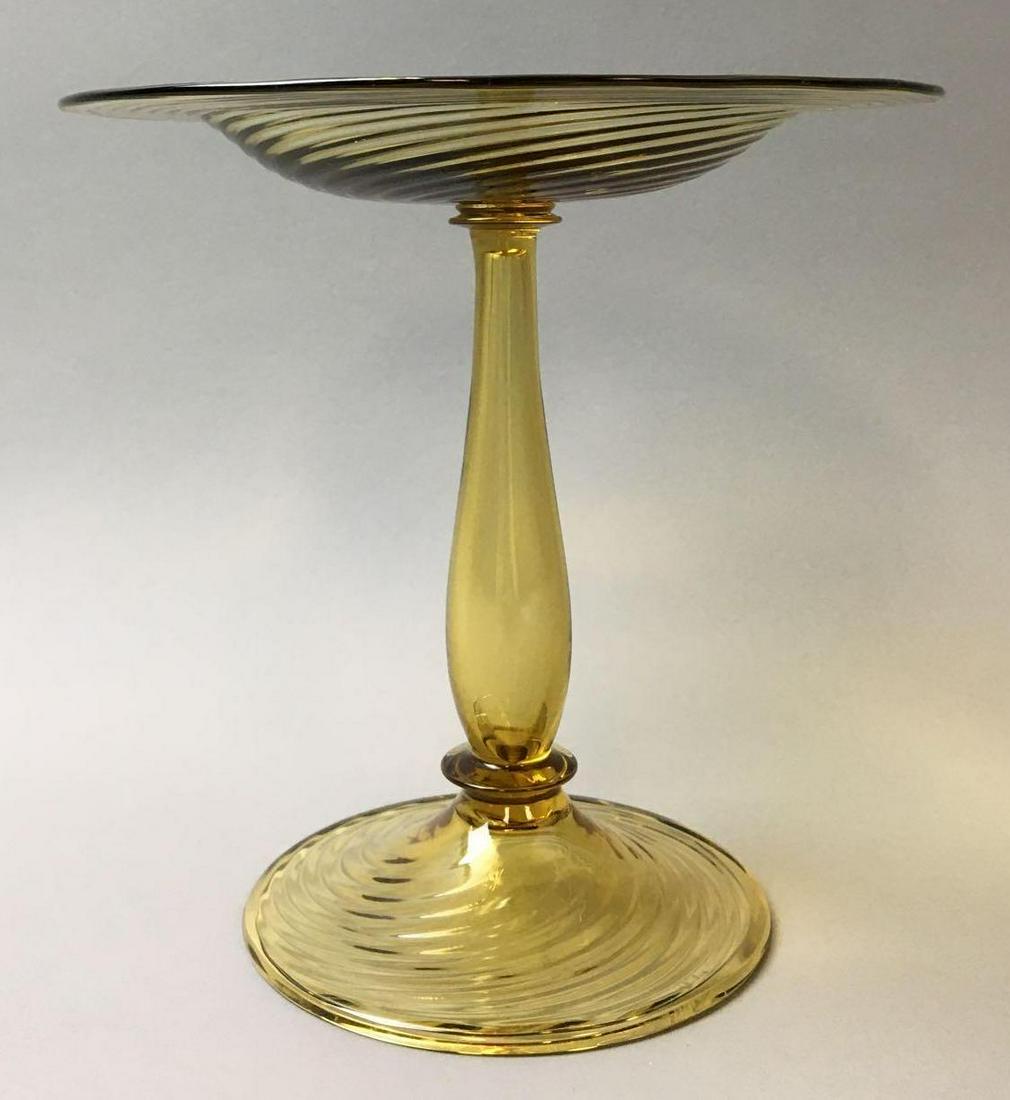 Steuben Amber Swirl Ribbed Compote: This Carder Steuben Amber Swirl RibbedCompote with folded rim measures 7 x 7 inches. It is signed "Steuben" in block letters on the base and is in excellent condition with no chips or repairs.