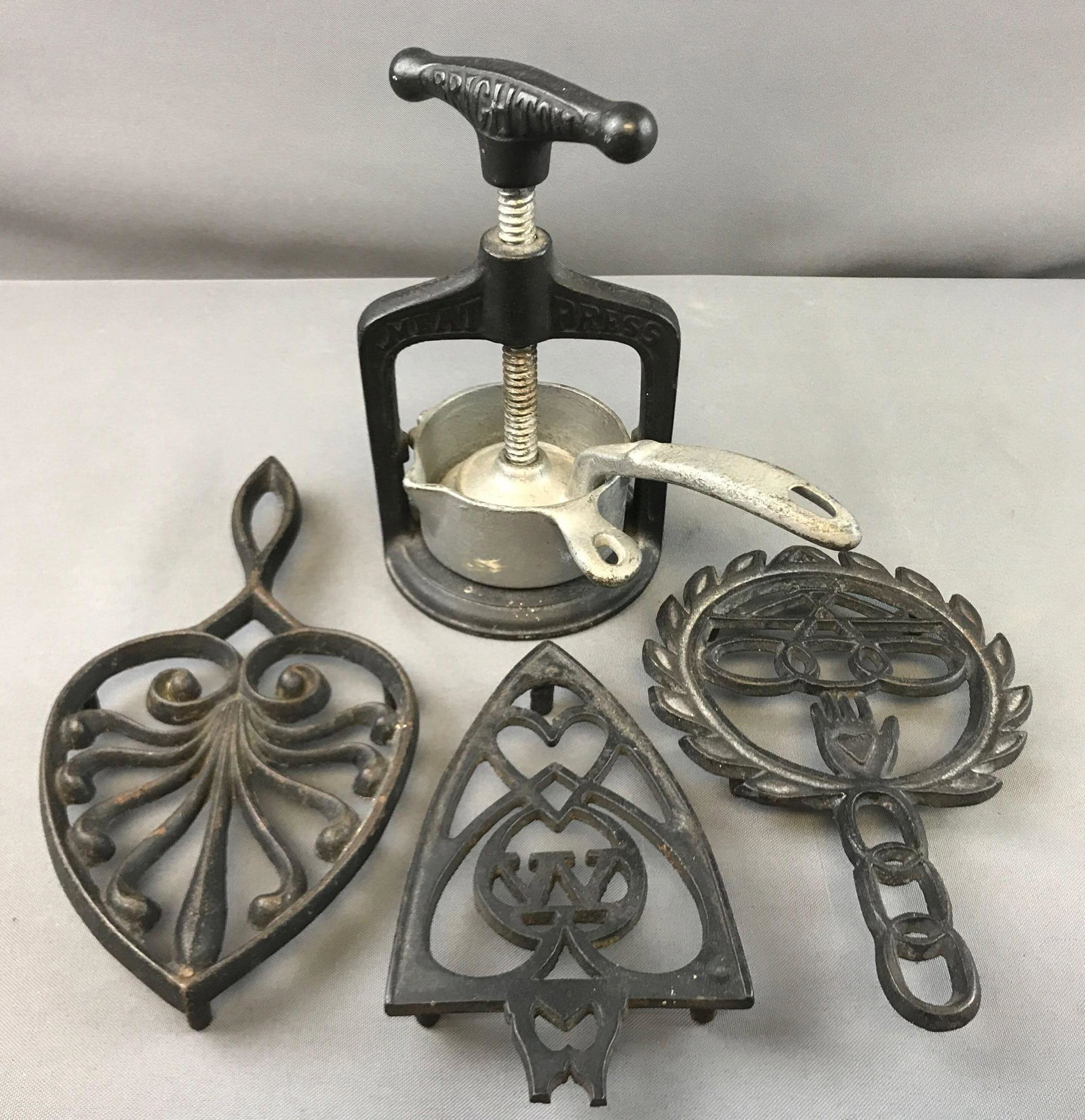 Group of 3 :Trivets and Antique Meat Press: Brighton meat press is 7 1/2 inches tall