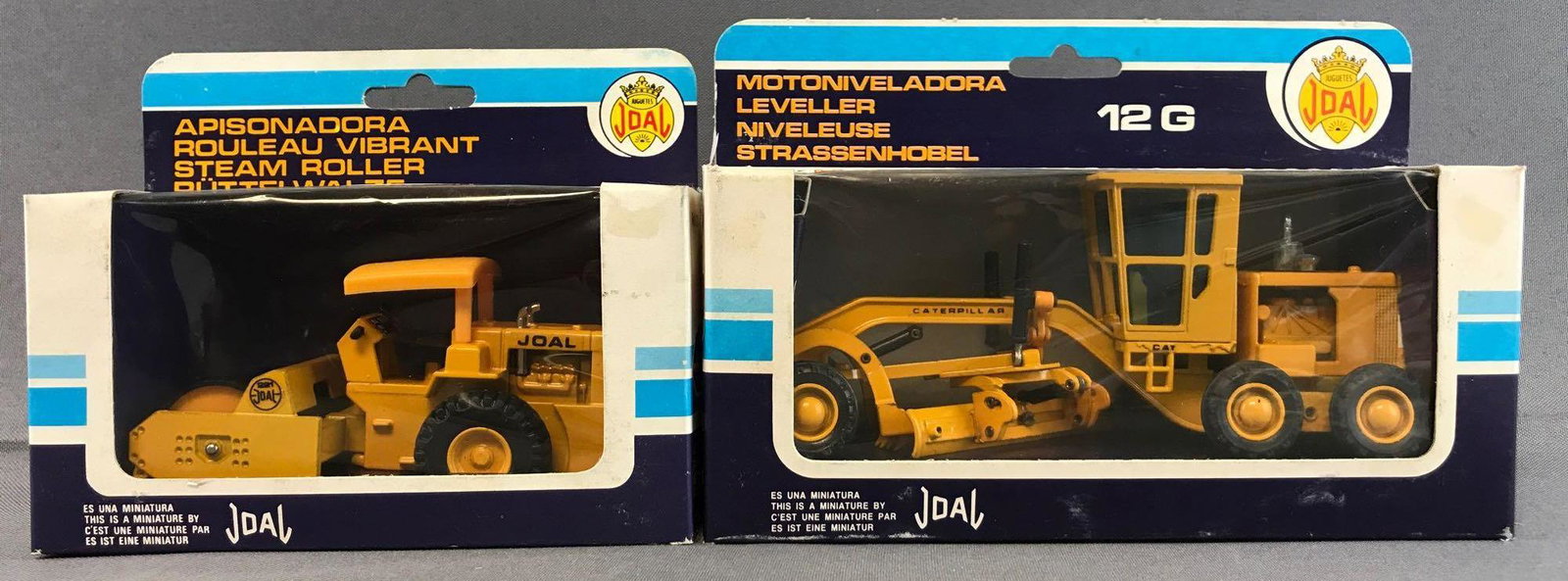 Group of 2 Joal Die-Cast Vehicles in Original Packaging: Includes No. 217 Caterpillar 12 G Leveller and No. 221 Steam Roller. Some damage to packaging