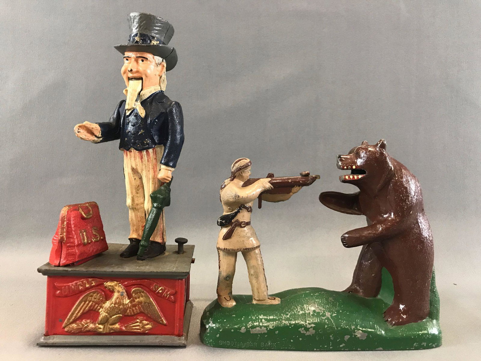 Group of 2: Vintage Cast Metal Mechanical Coin Banks: Larger Uncle Sam 1960-70s reproduction coin bank measures 4 3/4 x 4 x 11 1/4 inches. Smaller is circa 1950s Davy Crockett "Shoot-A-Bar" bank; both untested