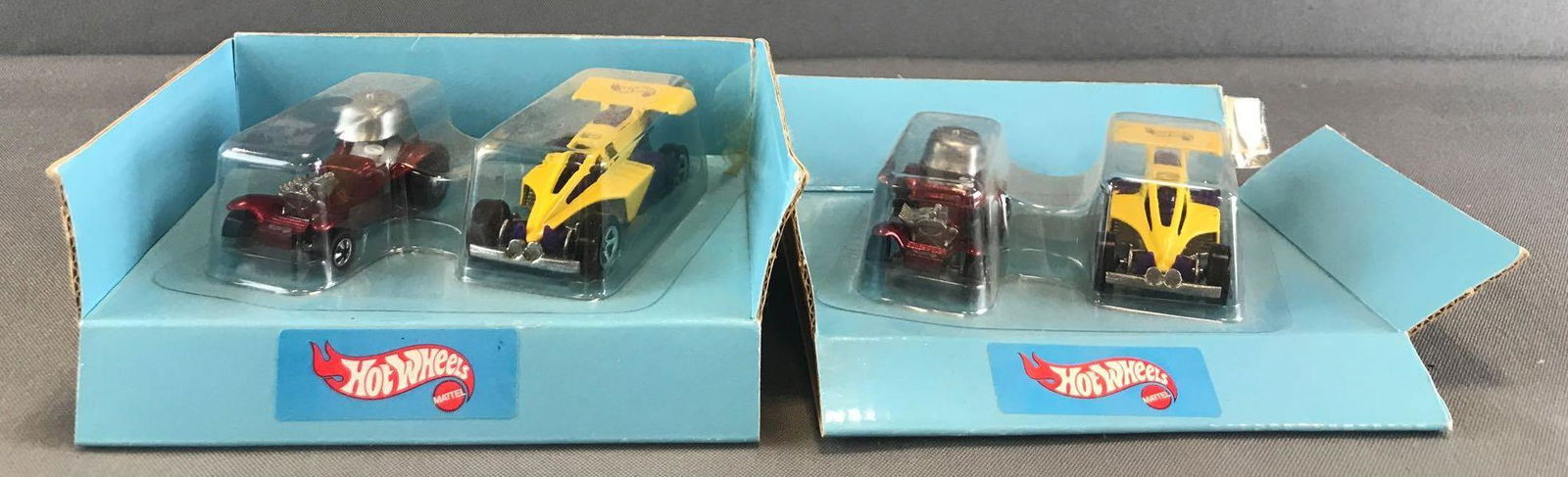 Group of 2 Hot Wheels die-cast vehicle sets with: Folded cardboard blister pack, includes Red Baron and Yellow Racer. Some minor damage to packaging