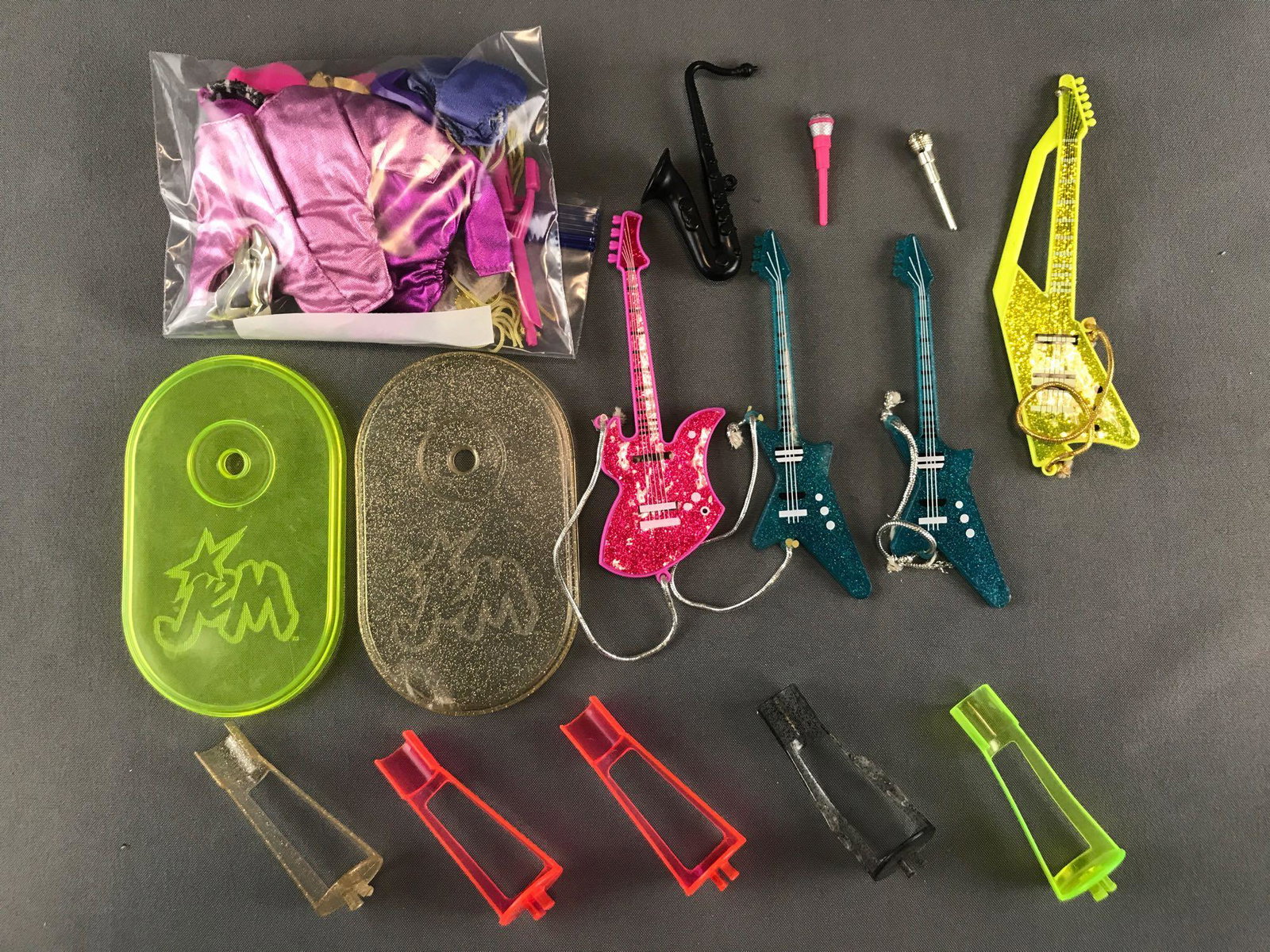 Group of 20+ assorted Hasbro Jem and the Holograms: Includes instruments, doll stands, clothing. Largest is 3.75x6.25 inches