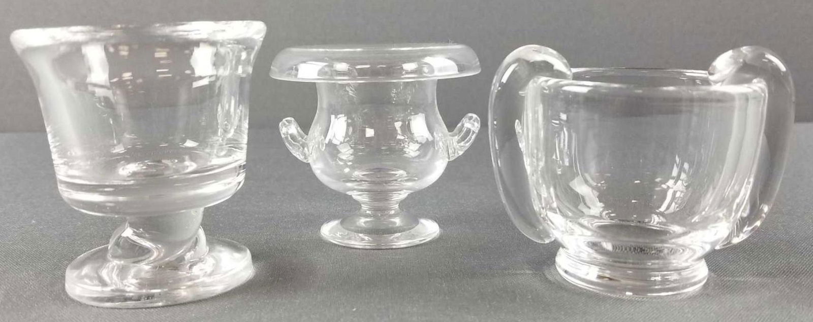 Group of 3 small glass candle holders: 2 Steuben. One marked S. Tallest is 3 inches. Some minor wear, mostly shelf wear on bottoms. No chips or cracks.