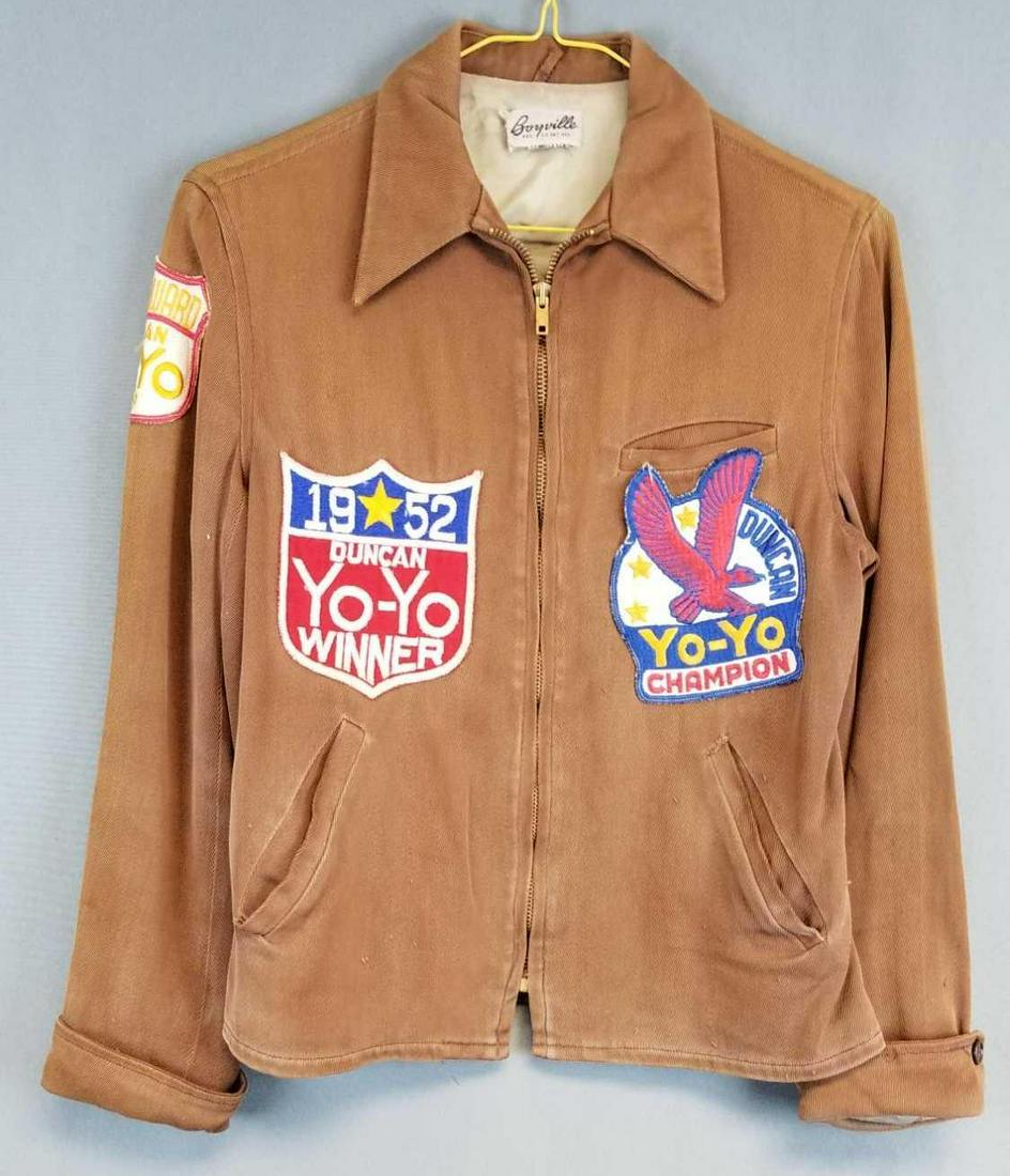 Vintage Duncan Yo-yo champion jacket: 1951-52 Duncan yo-yo winner patches affixed. By Boyville. Shoulder to shoulder 15, length 24. Brown with tan lining. Needs sewn inside arm.