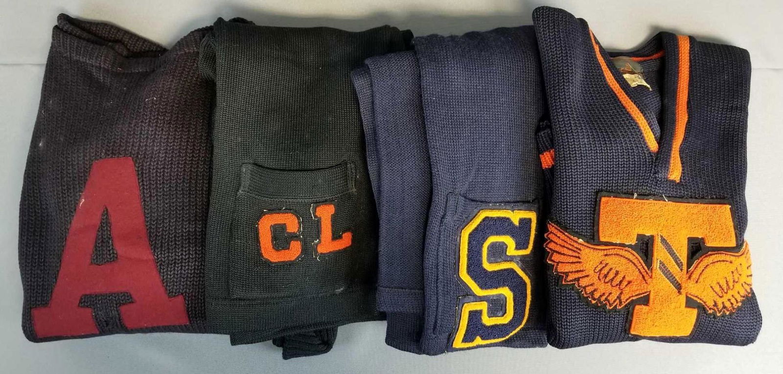 Group of 4 vintage letterman varsity sweaters: 2 pullovers, 2 cardigans. Black and navy blue. All have wear, stains, or holes