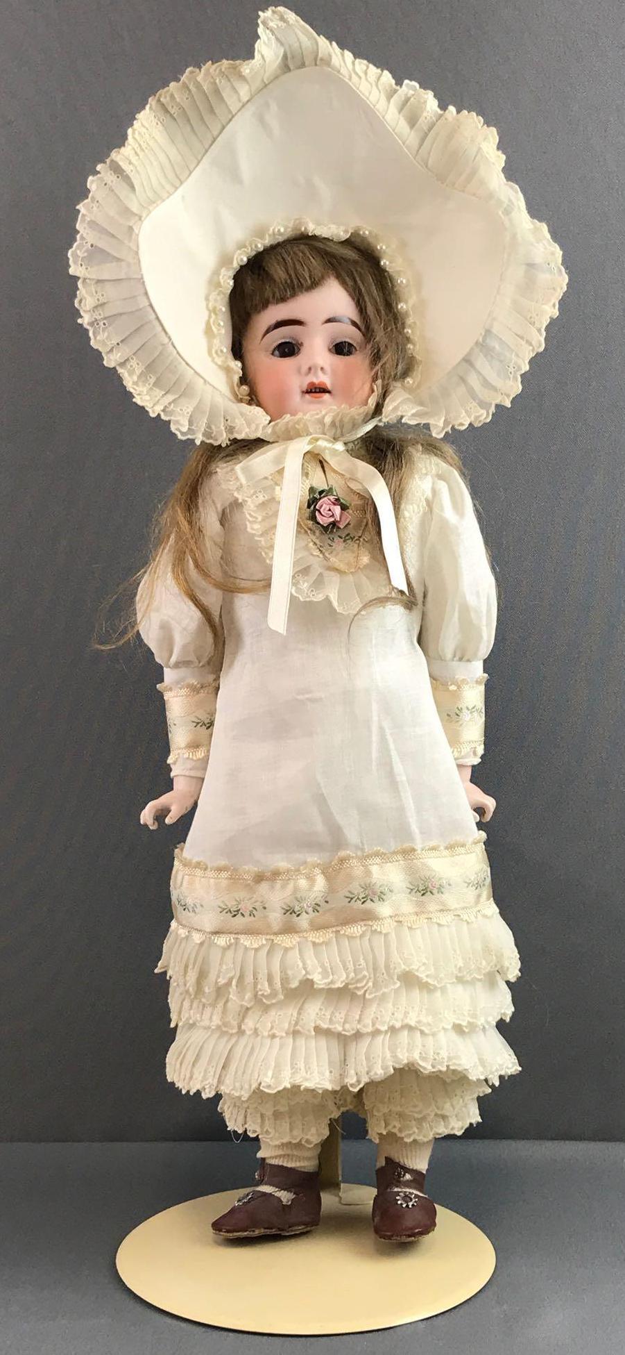 Antique 19 inch German bisque doll: Back of head reads H/5. Shoulder head, brown stationary glass eyes with painted lashes, pierced ears, open mouth with teeth, fabric body with bisque arms and legs. White dress, under garments, stockin