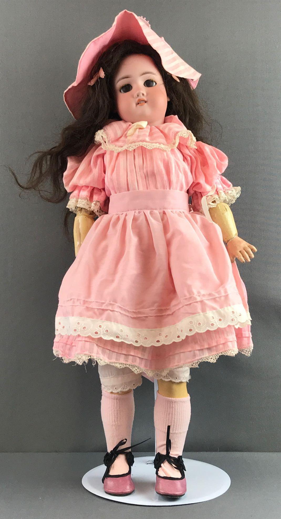Antique 24 inch German bisque doll Bergmann: Halbig, CM Bergmann, S&H. Socket head, brown sleep eyes with painted and applied lashes, composition and wood jointed body. Pink dress, hat, under clothing, socks, shoes. Brown hair wig. Paint loss, c