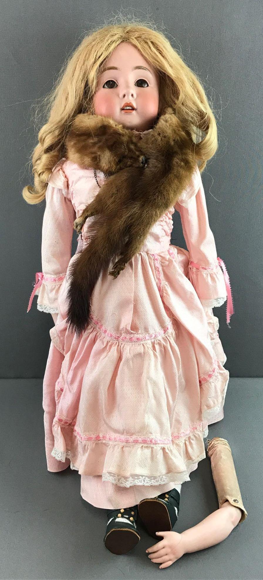 Antique 30 inch German bisque doll: Head marking reads Dep 154.15. Shoulder head, brown sleep eyes with painted and applied lashes, leather body, bisque arms. Pink dress, mink stole, under garments, stockings, shoes. Arms are loose from