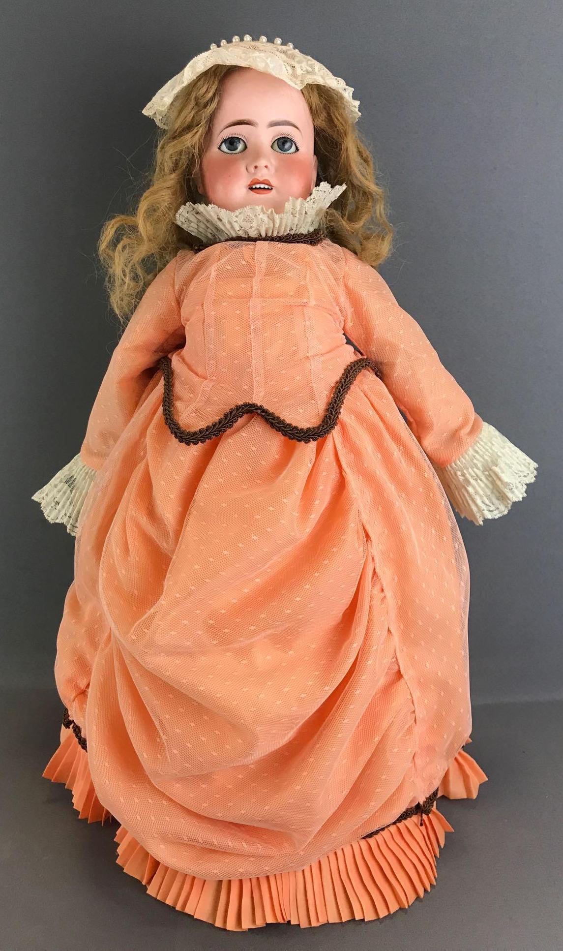 Antique 24 inch French bisque doll Limoges: Back of head reads Limoges France, 10. Socket head, blue stationary glass eyes, open mouth with teeth, pierced ears, composition and wood jointed body. Peach dress with lace, under gaments, hat, socks