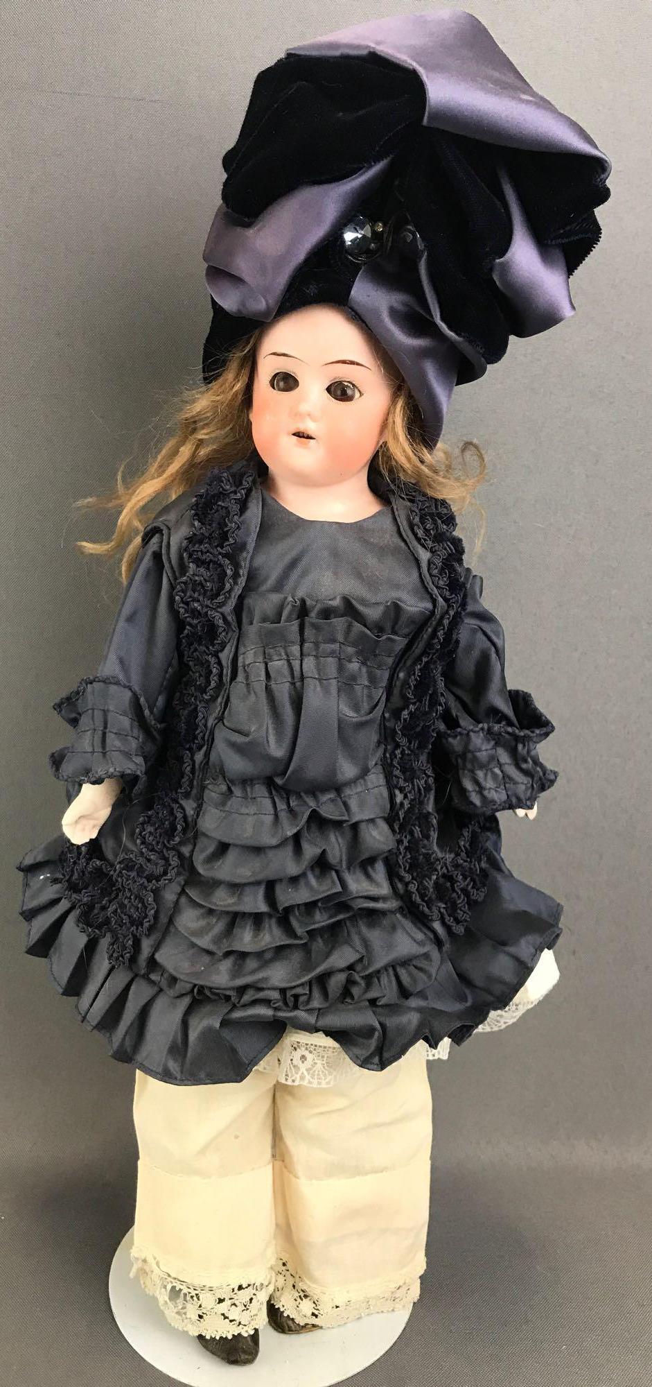 Antique 14 inch German bisque doll Dressel Holz-Masse: Germany, winged helmet, 13/0. Shoulder head, brown glass sleep eyes with painted lashes, leather body with bisque hands. Brown hair wig, attached. Navy blue dress, hat, under garments, boots. Paint lo