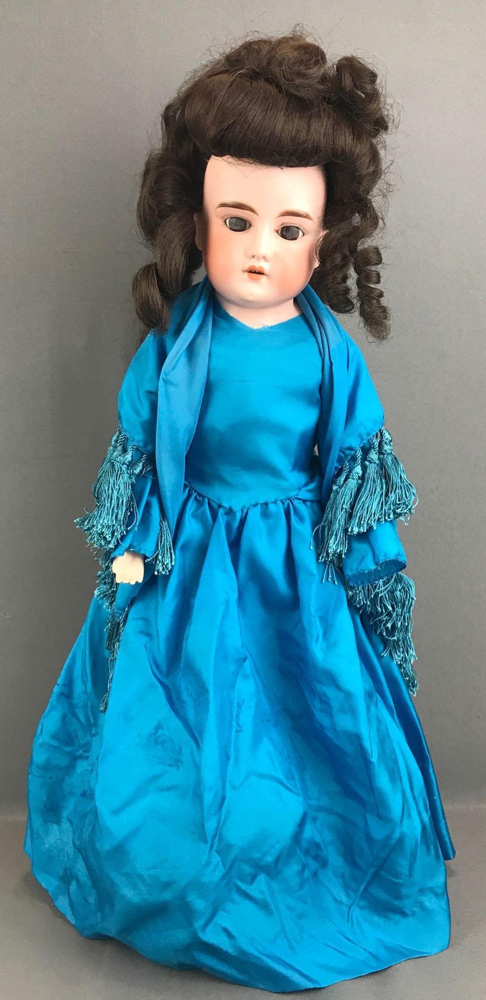 Antique 21 inch German bisque doll Marseille: Lilly, 2, made in Germany. Shoulder head, brown glass sleep eyes with painted lashes, leather body, bisque arms, open mouth with teeth. Blue dress, under garments, stockings. Brown replacement wig, un