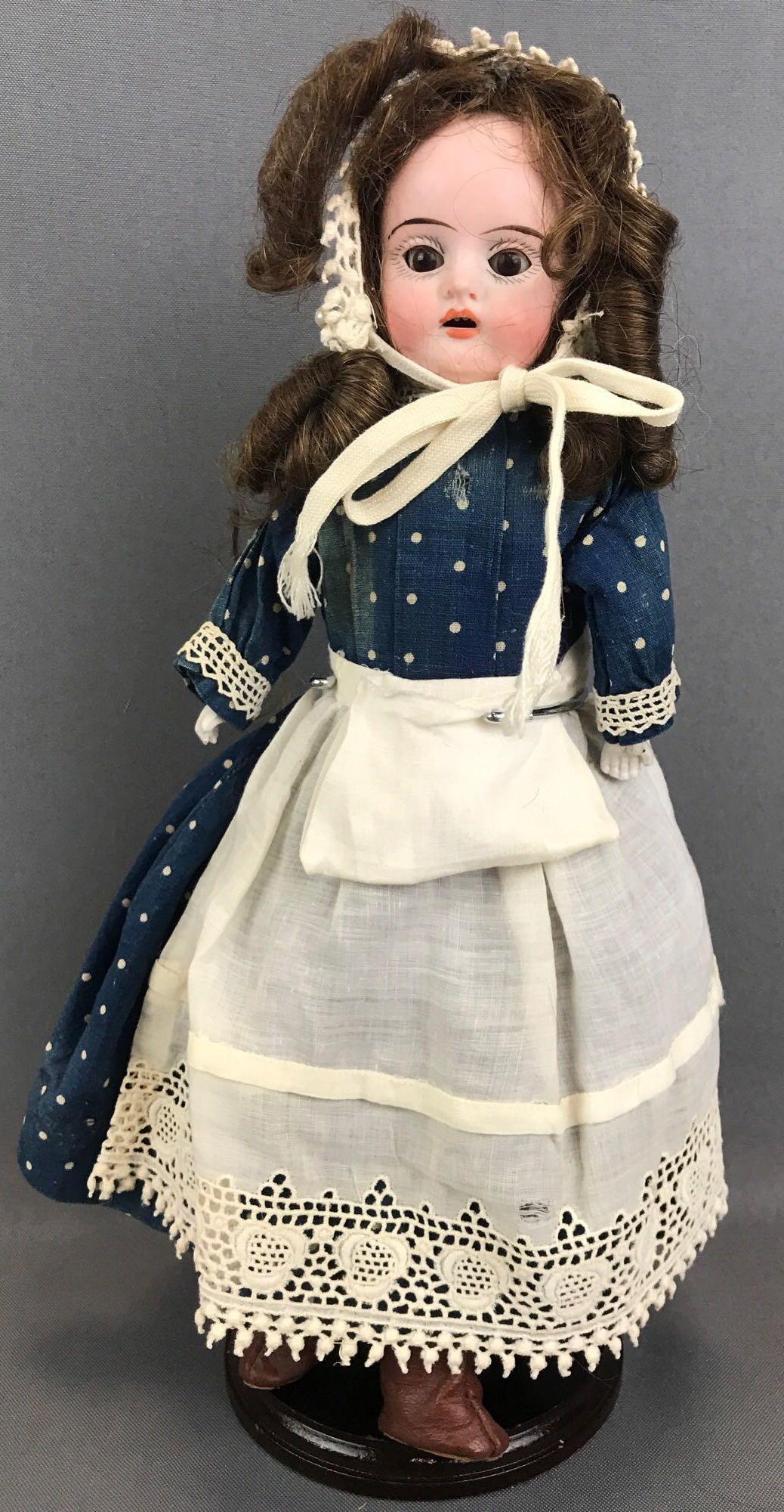 Antique 13.5 inch German bisque doll: Head reads 14/0, no other marks. Shoulder head, open mouth with teeth, brown glass sleep eyes with painted lashes, leather and fabric body with bisque hands. Blue polka dot dress with apron, bonnet, b