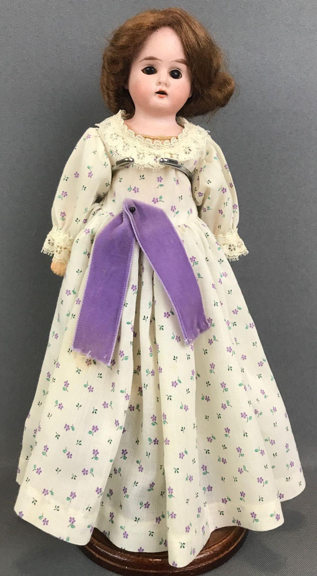 Antique 12 inch German bisque doll Heubach: Head has horseshoe symbol, 1902-15. Shoulder head, brown stationary eyes, no lashes, open mouth with teeth, leather and fabric body with composition hands. Ivory colored floral dress, bloomers, socks,