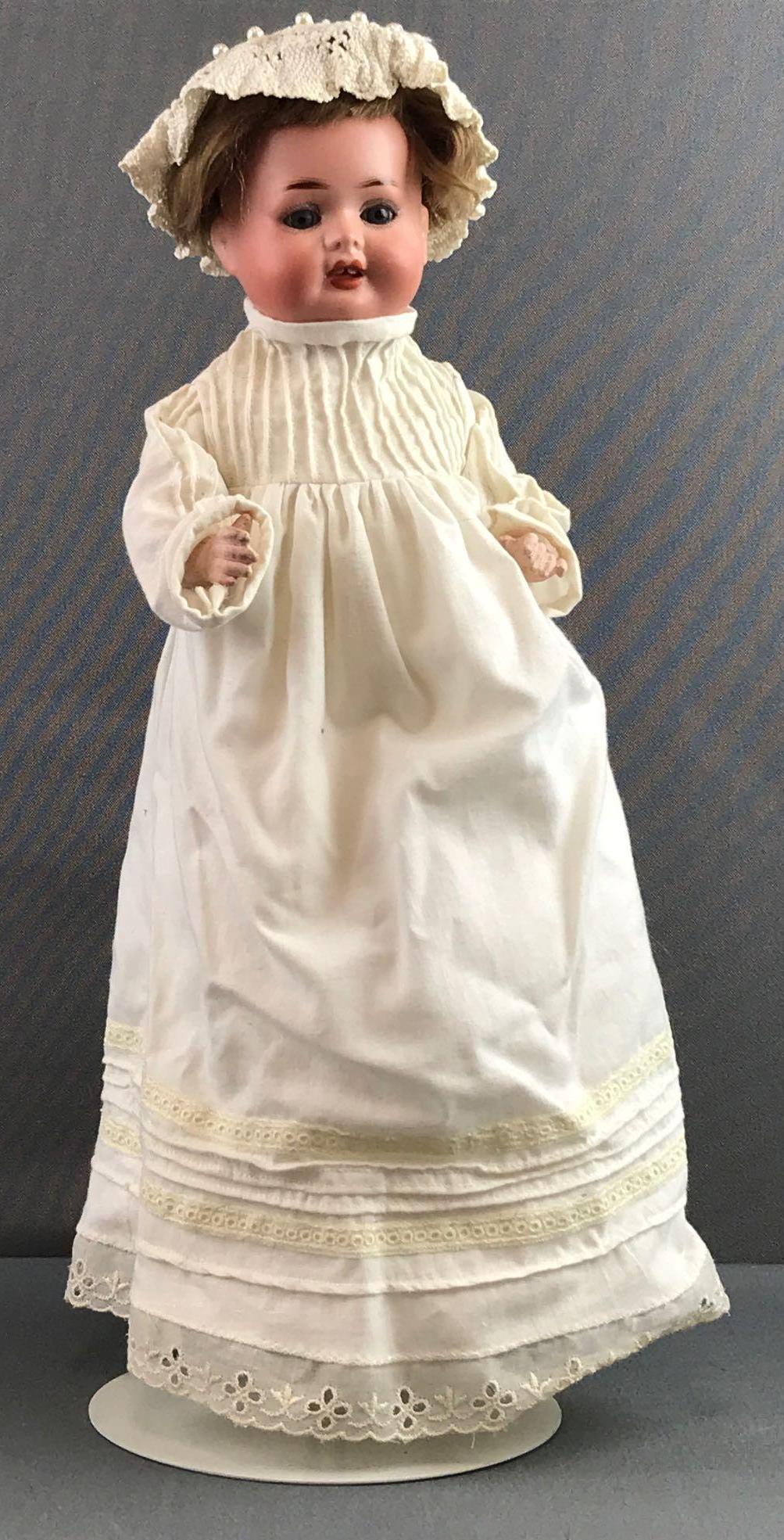 Antique 12 inch German bisque ba doll Recknagel: R86A, 3/0. Socket head, blue glass sleep eyes with painted lashes, open mouth with 2 top teeth, composition body with bent limbs. Brown wig, attached. Usual wear to body and limbs, fingers have paint 