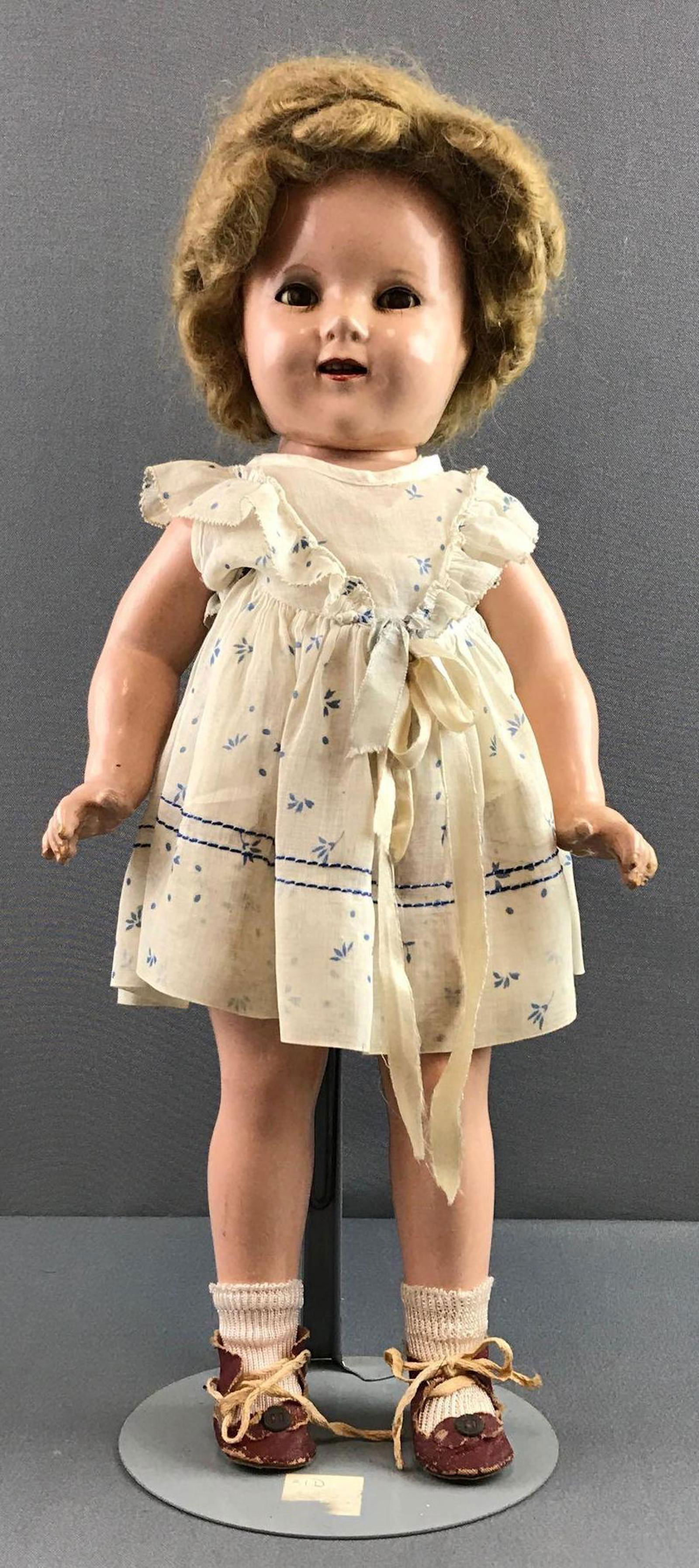 Vintage Ideal Shirley Temple doll: Composition head and body, some finish issues- cracks, chipping. Mohair wig, attached. Measures 18 inches. Doll stand not included.