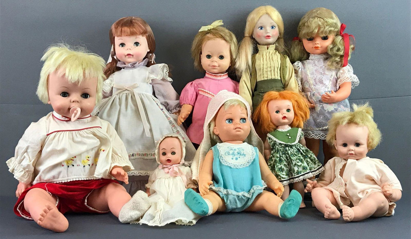 Group of 9 assorted sleep eye dolls: Includes Deluxe Reading Corp, Chatty Cathy, Sugar Darlin by Madame Alexander and more. Largest measures 18.35x21x4.5 inches. Some markings and clothing stains, in used condition.