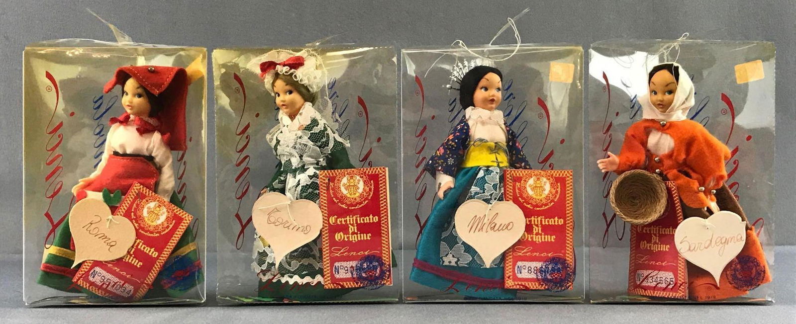 Group of 4 Lenci Folklore dolls in original packaging: Includes Roma, Milano, Sardegama and Corina. Measures 4.5x8x2.5 inches. Like new condition.