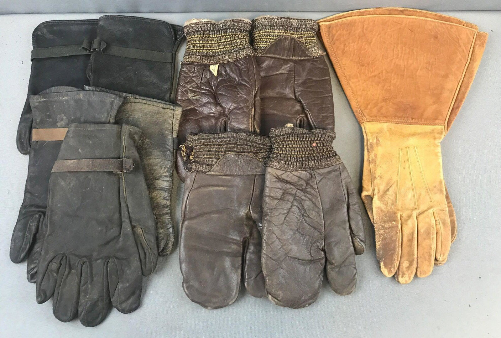 Group of 11 assorted Leather Gloves: Includes 2 pair Military 3-fingered Gunner gloves, (1) pair gauntlets, and more. Largest is 16 inches
