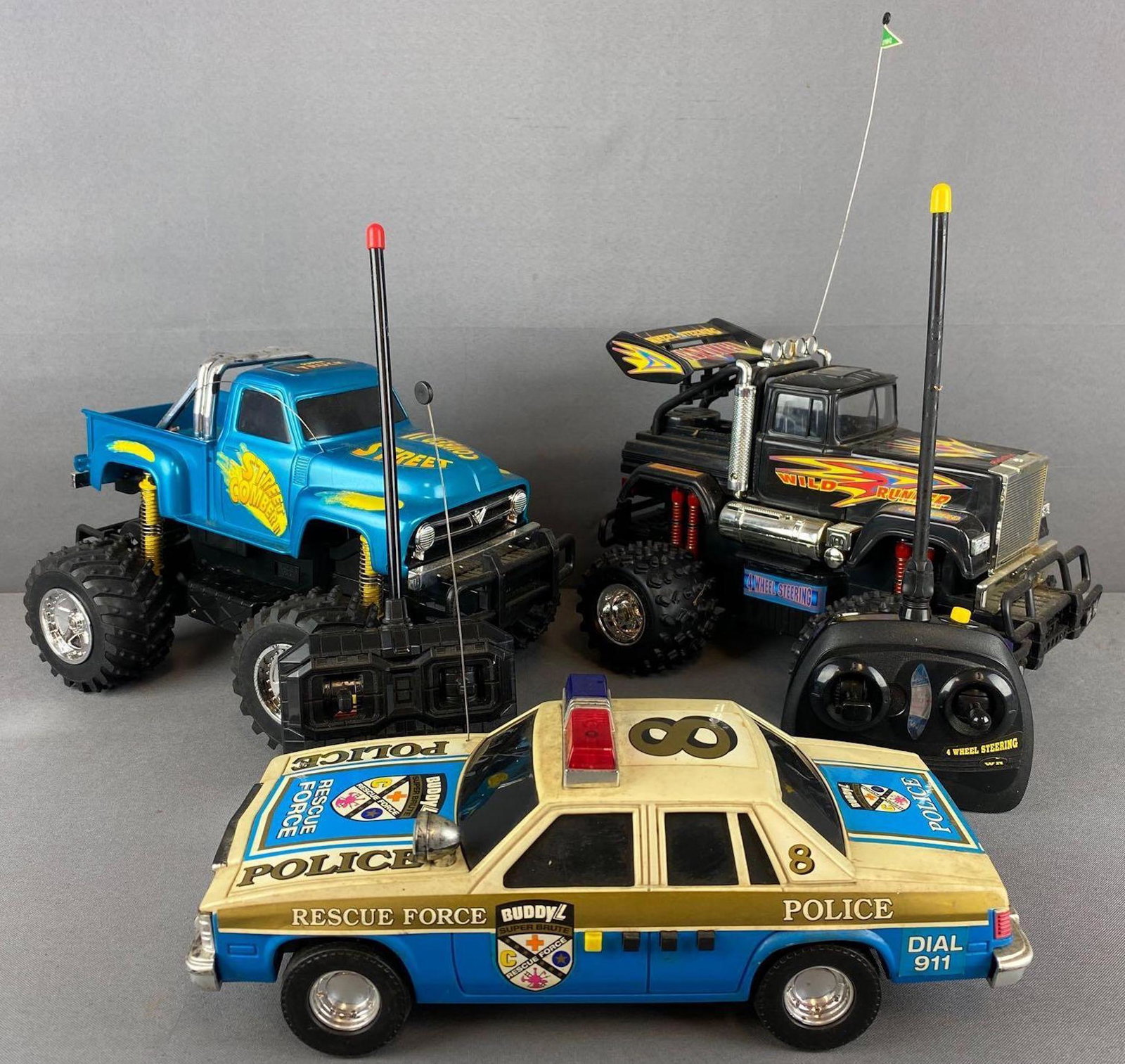 Group of 3 assorted battery powered and RC vehicles: Plastic, Buddy L Police car without R/C. Largest is appx 12.5x9x9 inches.Untested