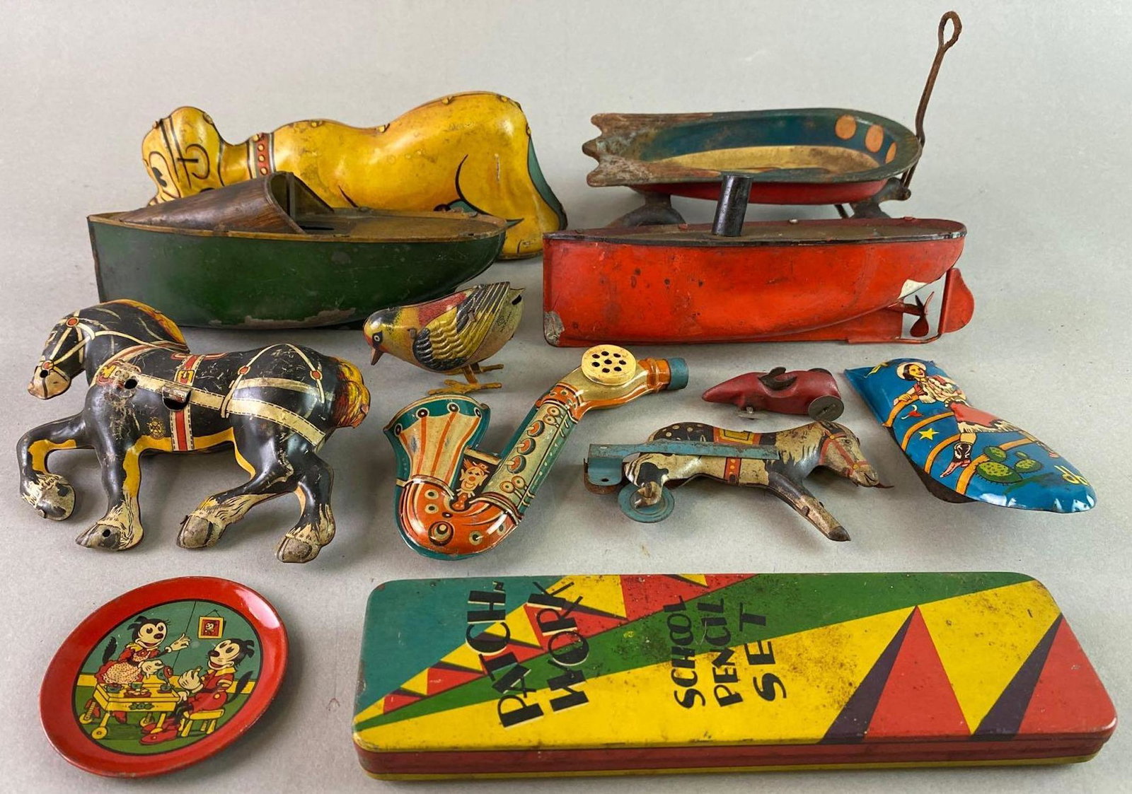 Group of 12 Tin Toys: Includes Disney, Boats, Kazoo, Clicker. Kazoo and bird work. Pluto measures approximately 8 x 2 1/2 inches.