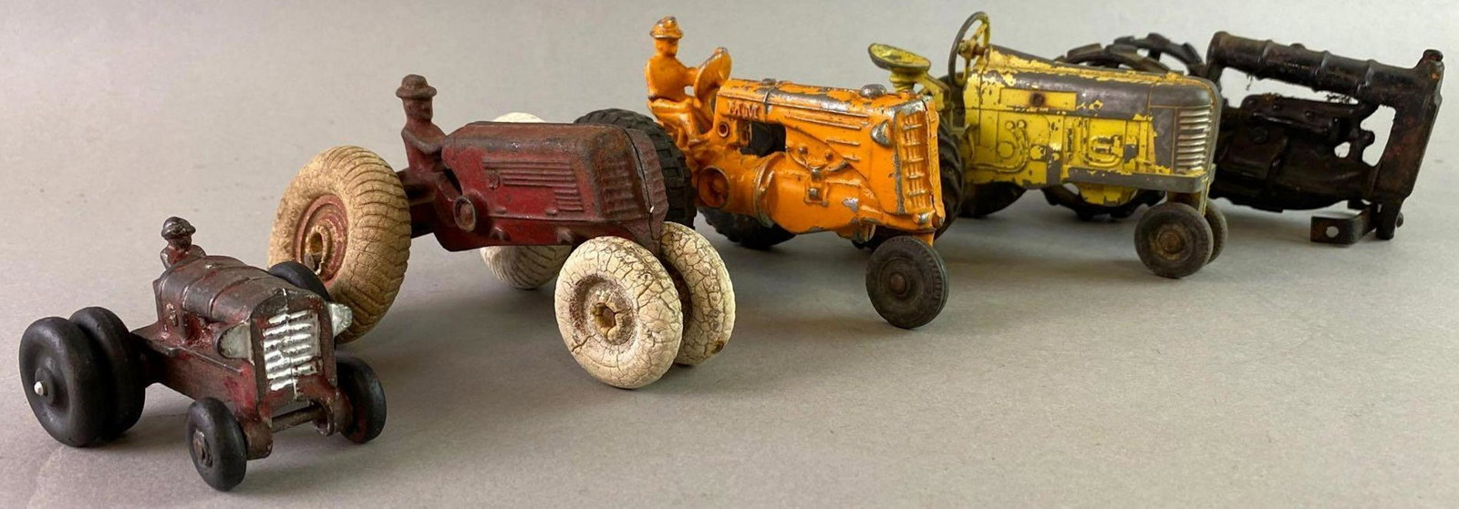 Group of 4 Antique Cast Iron Diecast Toy Tractors: Includes 1 Arcade. Yellow tractor measures approximately 5 1/2 x 3 inches.