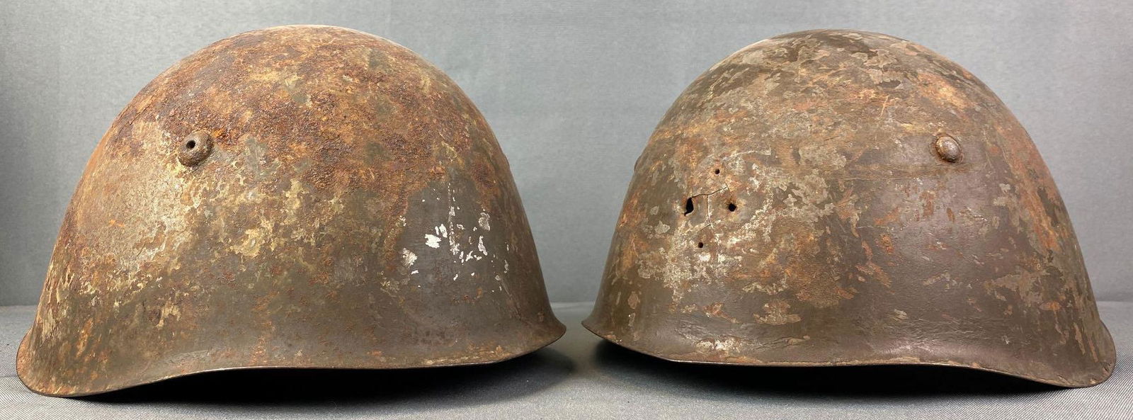 Group of 2 WW2 M33 Italian Helmets: Rusted, one has holes, chinstrap and liner are intact, one chinstrap is ripping, largest is 9.25X11x6.5 inches