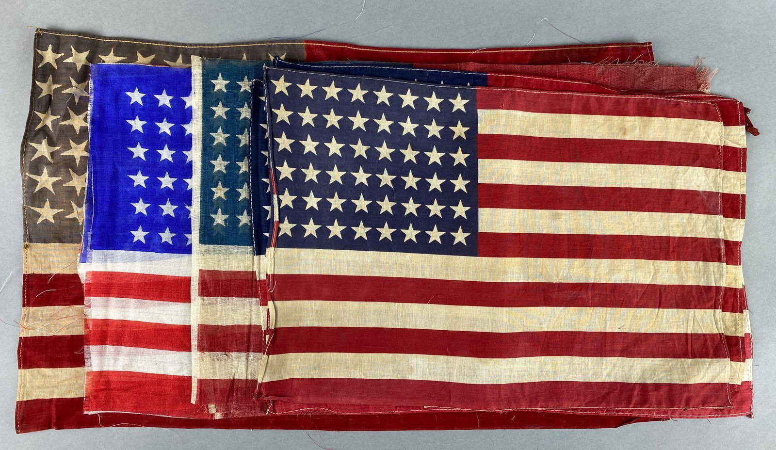 Group of 10, 48 Star Flags: The largest measure 22 x 13 1/2 inches. There is some damage and staining.