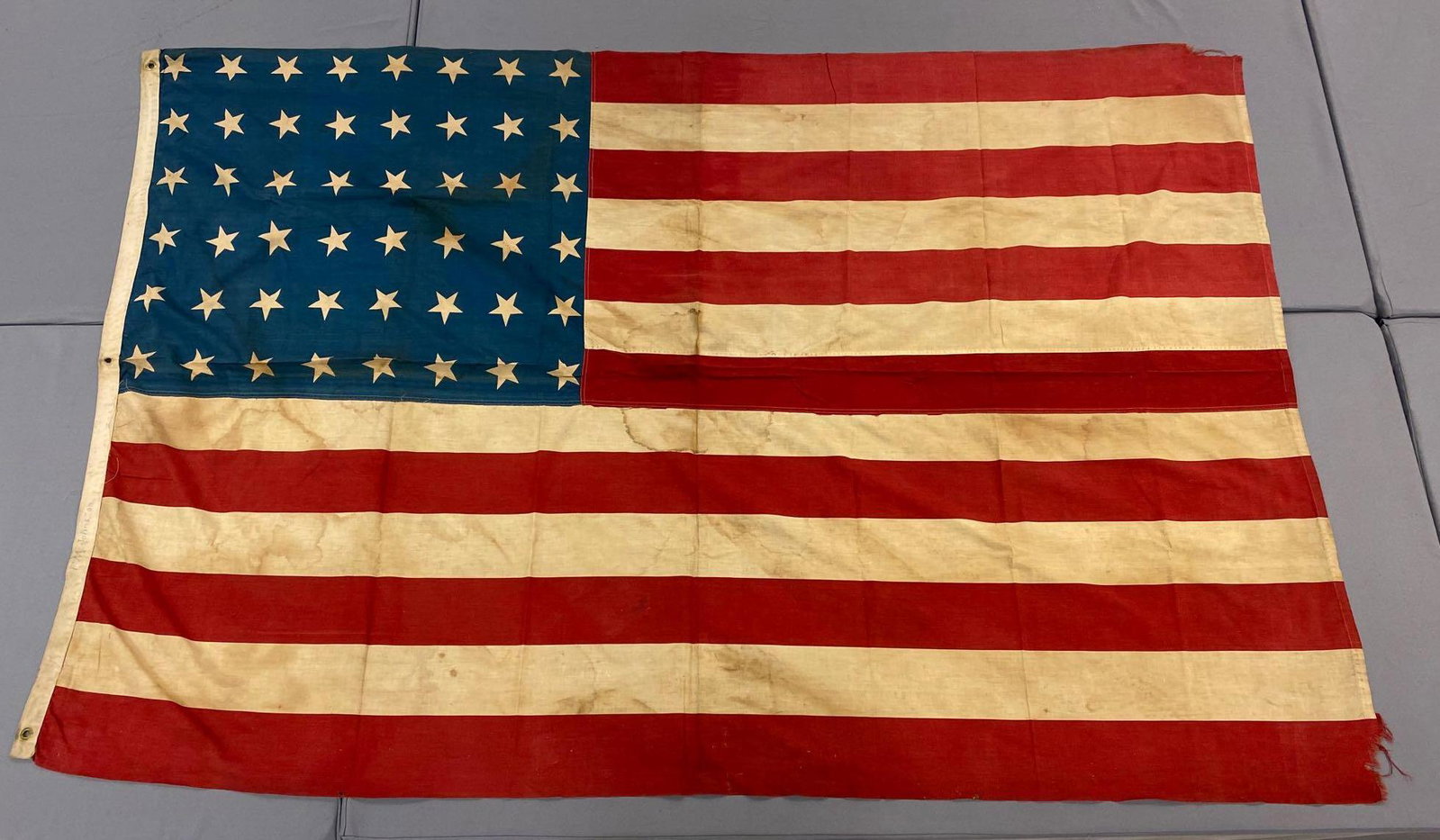 48-Star US Flag: 85x59 inches, machine sewed cotton, printed Stars and Stripes, frayed corner, discoloration
