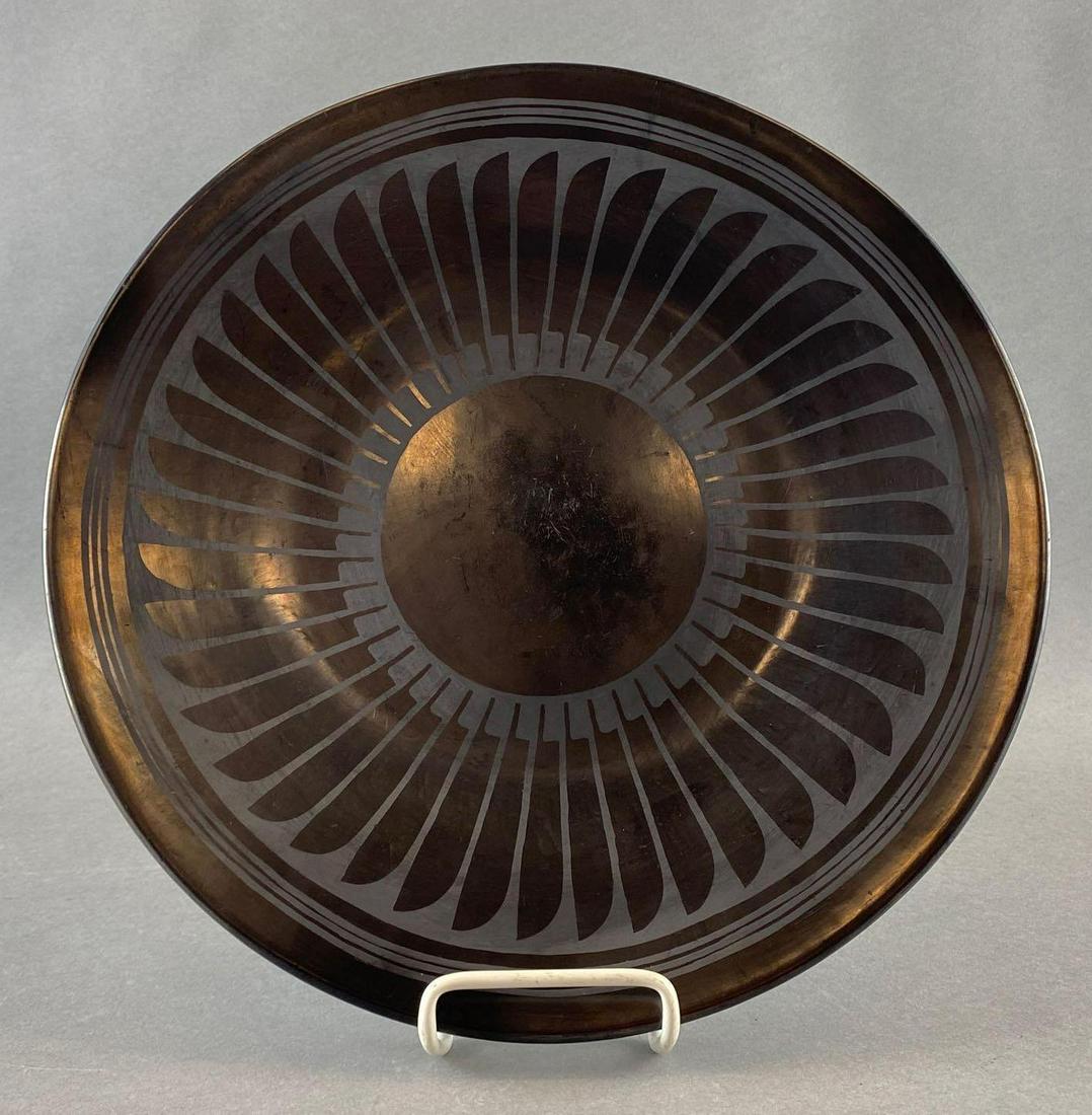 Maria and Santana Native American Feather Plate: Black redware plate with painted feather design. San Ildefonso Pueblo artist. Signatures on back. Measures 12.75in in diameter.