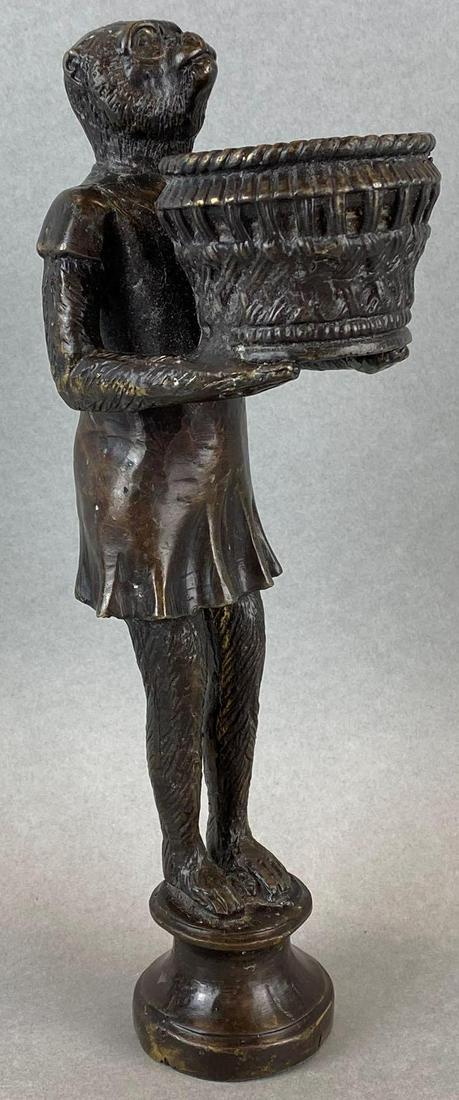 Brass Statue of Monkey in Dress Holding Basket: Some scratches and marks. Does not stand flat. Measures 11.5in tall.