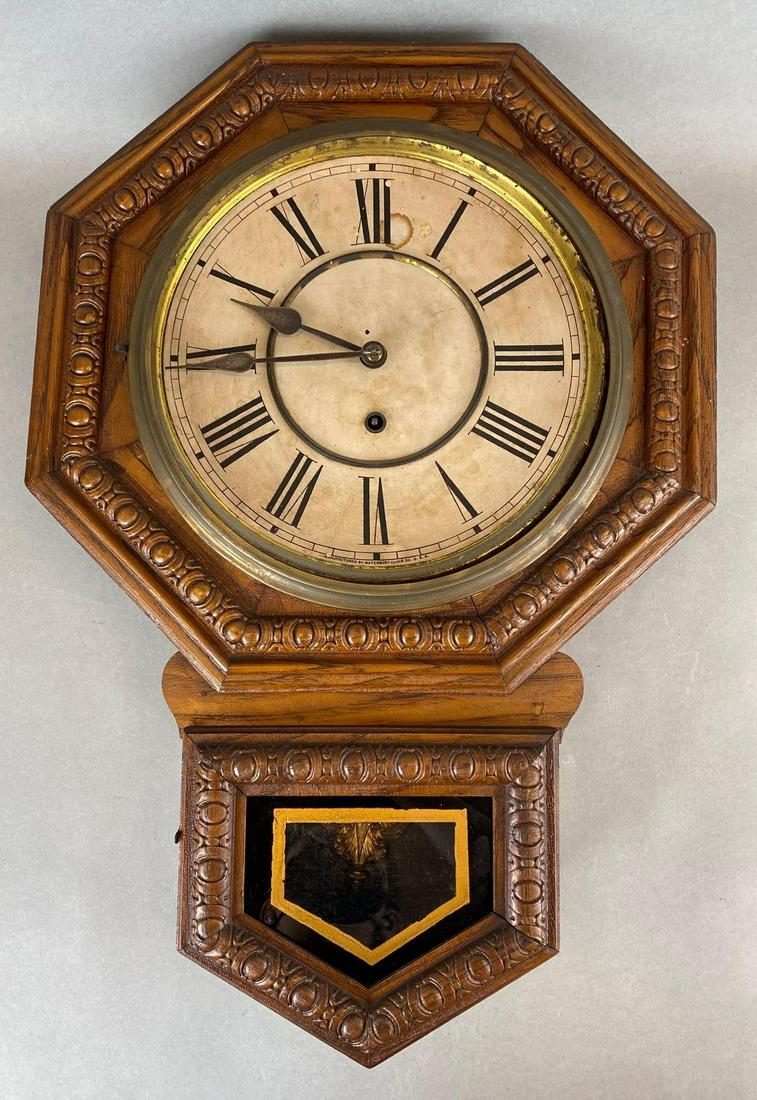Waterbury Clock Co. Wall Hanging Clock: Made in the US, missing front glass, metal face in wood casing, missing wind key, some tarnishing on face, untested, measures 23in tall.