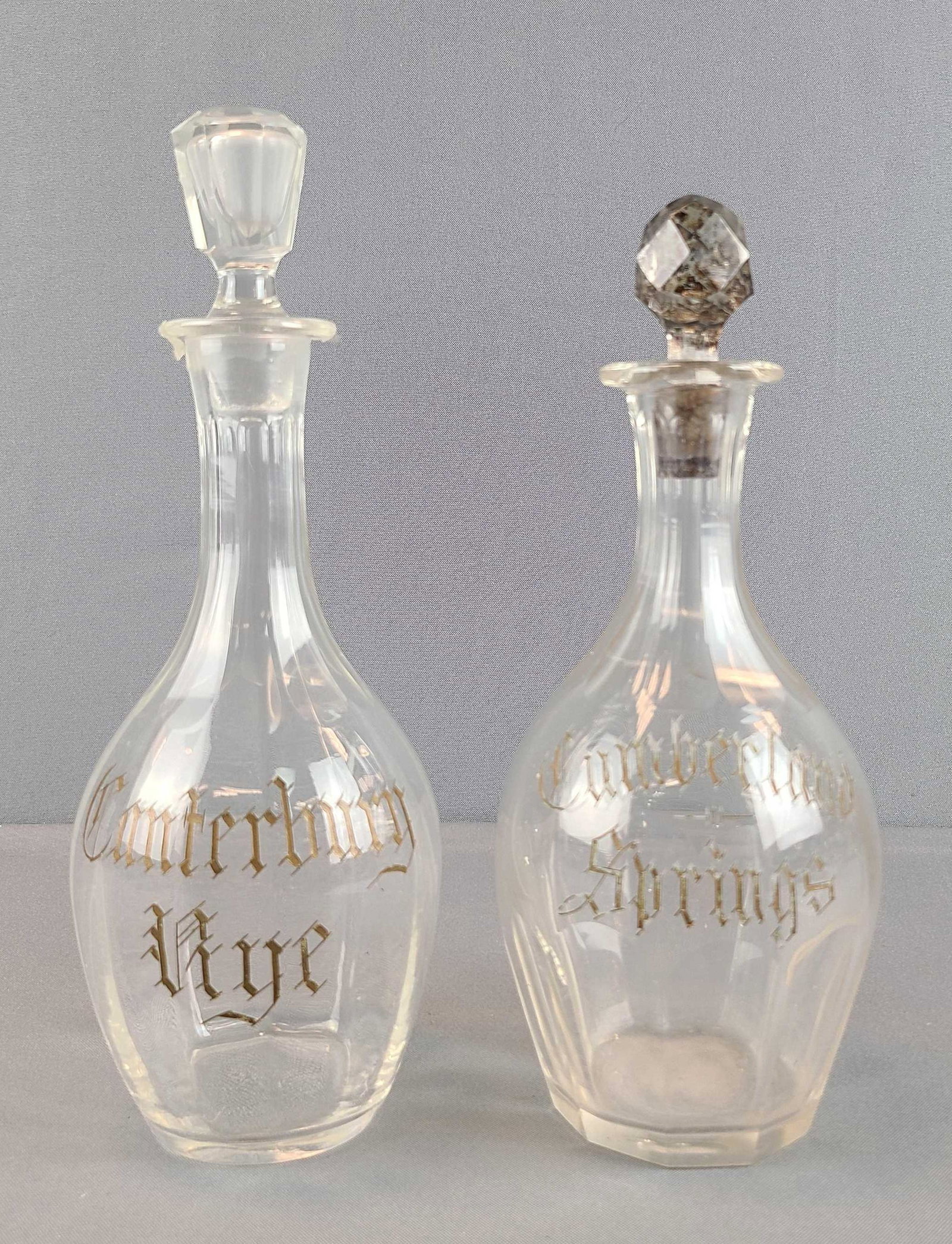 Group of 2 Pre-prohibition Bar Back Saloon Bottles: Whiskey and Rye liquor bottles. Canterbury Rye, Cumberland Springs. Includes 2 stoppers. Larger bottle is 9 1/2 inches tall