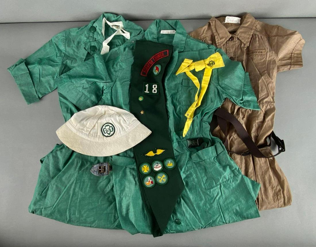 Group of Girl Scout Uniforms and Accessories: Includes 3 dresses, 3 belts, 1 sash, 1 hat, and 1 bow, Largest dress measures 34in collar to hem, 13 1/2in shoulder to shoulder, and 9in shoulder to cuff.