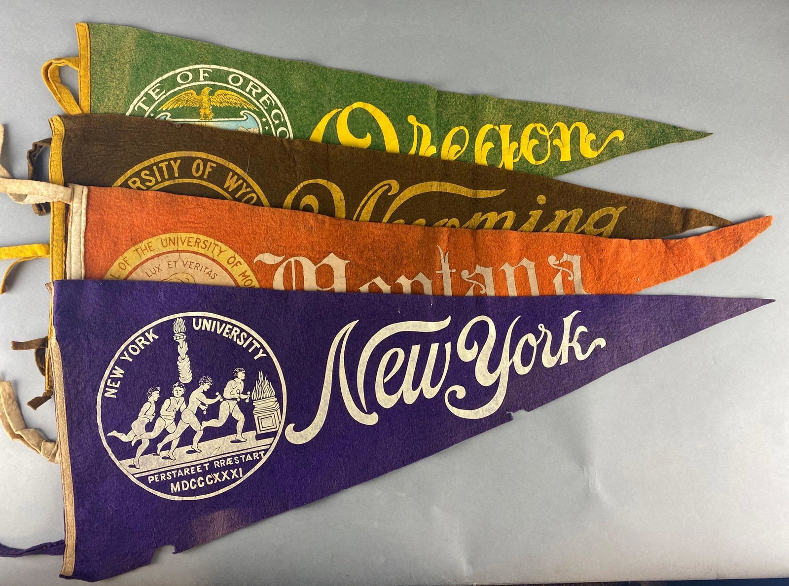4 - Early Large University Pennants: New York UniversityUniversity of MontanaUniversity of WyomingUniversity of OregonMeasures 35, 35, 35 1/2, 32 1/2 inches
