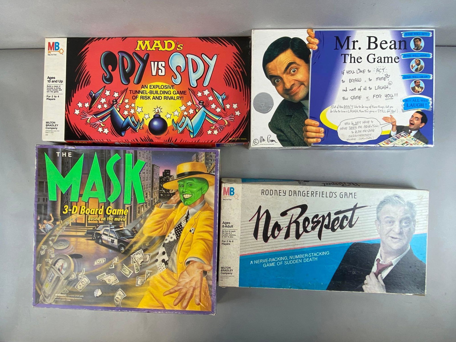 Group of 4 Pop Culture Board Games: Includes Mads Spy Vs Spy, The Mask 3-D Board game, Mr. Bean the Game, and Rodney Dangerfield No Respect Game (box covered in tape), Unknown set completions, Some holes in boxes and boards from hanging