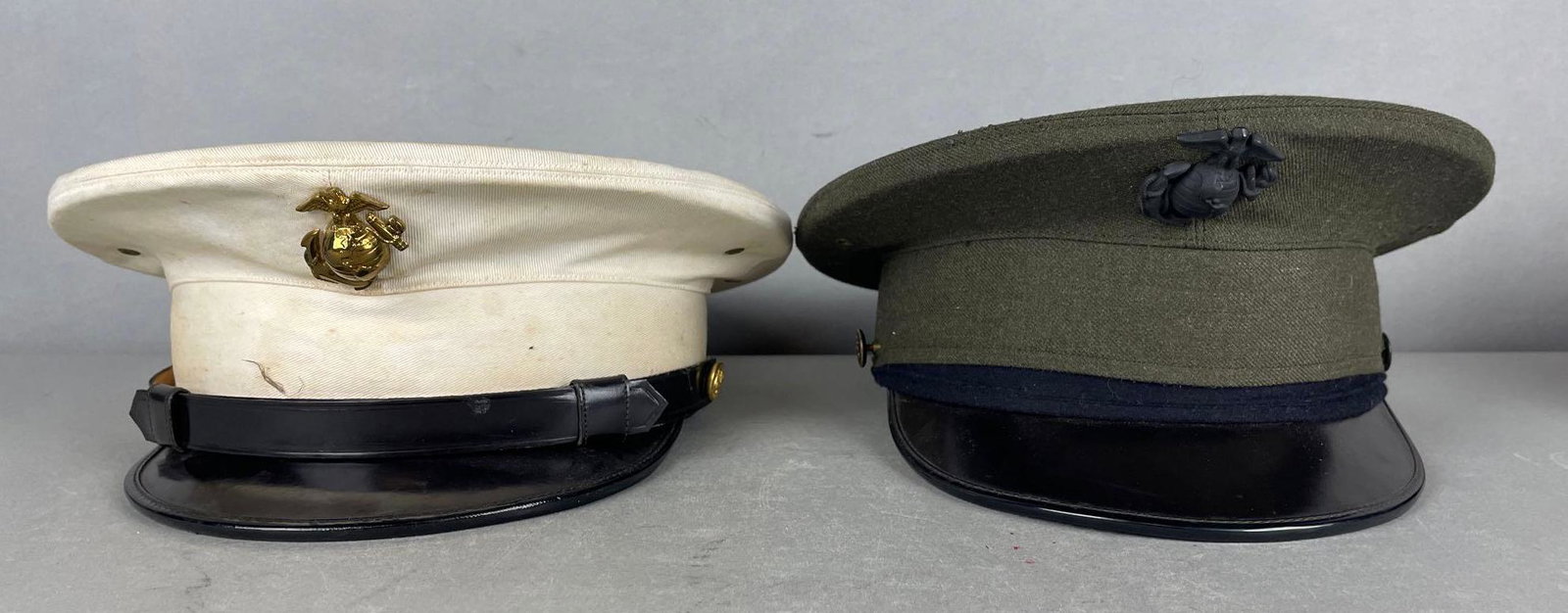 Group of 2 USMC Caps: White dress hat has staining, size 7 1/4. Green officers cap is missing strap, has some small moth holes on top. Size 7 1/4