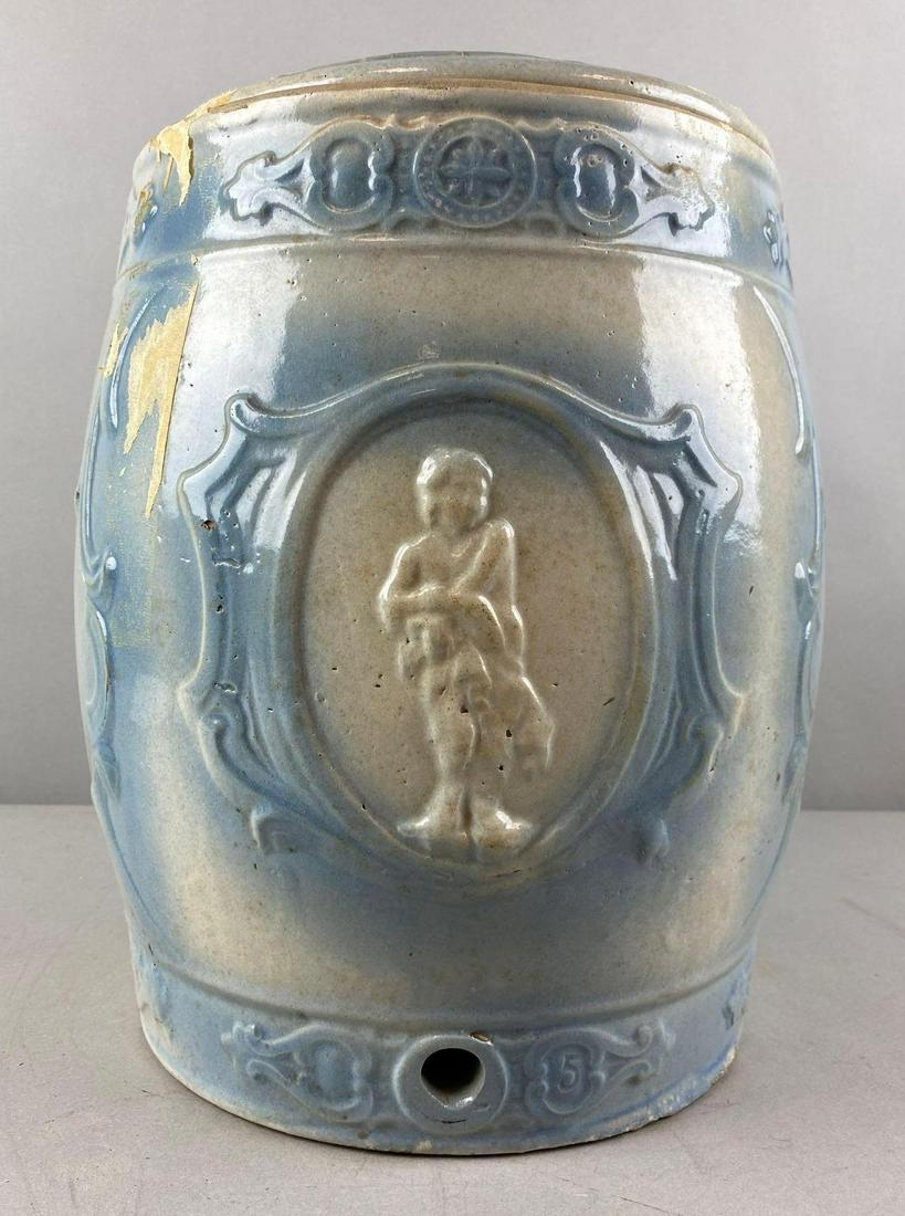 Western Stoneware Cupid Blue and White Lidded Water Cooler: Hole for cork. tape residue. Small chips. Measures 15 x 9 1/2 inches
