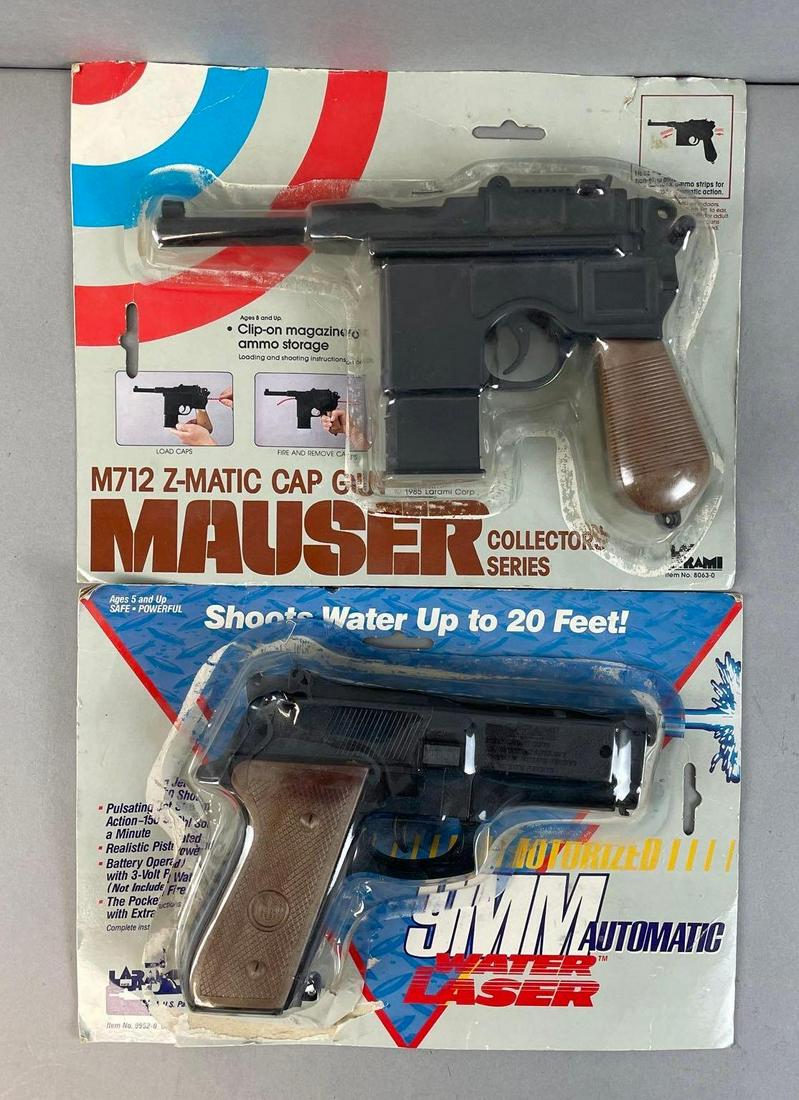 Group of 2 Toy Pistols: Includes Larami Mauser cap gun, and 9mm automatic water laser. Both in original packaging that has been stapled back shut. Largest package measures 9 x 11 1/2 inches
