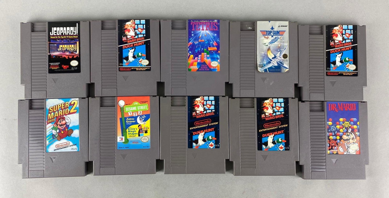 Group of 10 Nintendo NES Game Cartridges: Includes Super Mario Bros/Duck Hunt, Dr. Mario, Tetris, Top Gun, and more. Measures 4 1/2 x 5 inches
