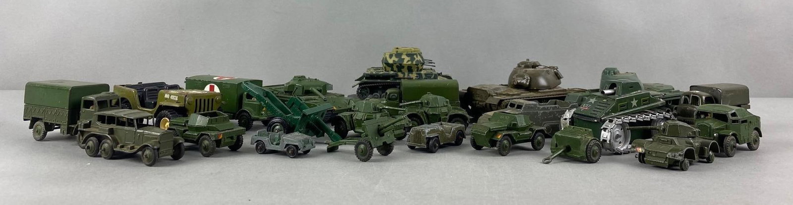 Group of 20+ Assorted Military Vehicles: Majority die-cast, includes Dinky Toys 670 British Armored Car, Dinky Toys 689 Field Artillery Tractor, Dinky Toys 686 25 Pounder Field Gun, and more. Largest measures 5 1/2 x 3 x 2 1/4 inches