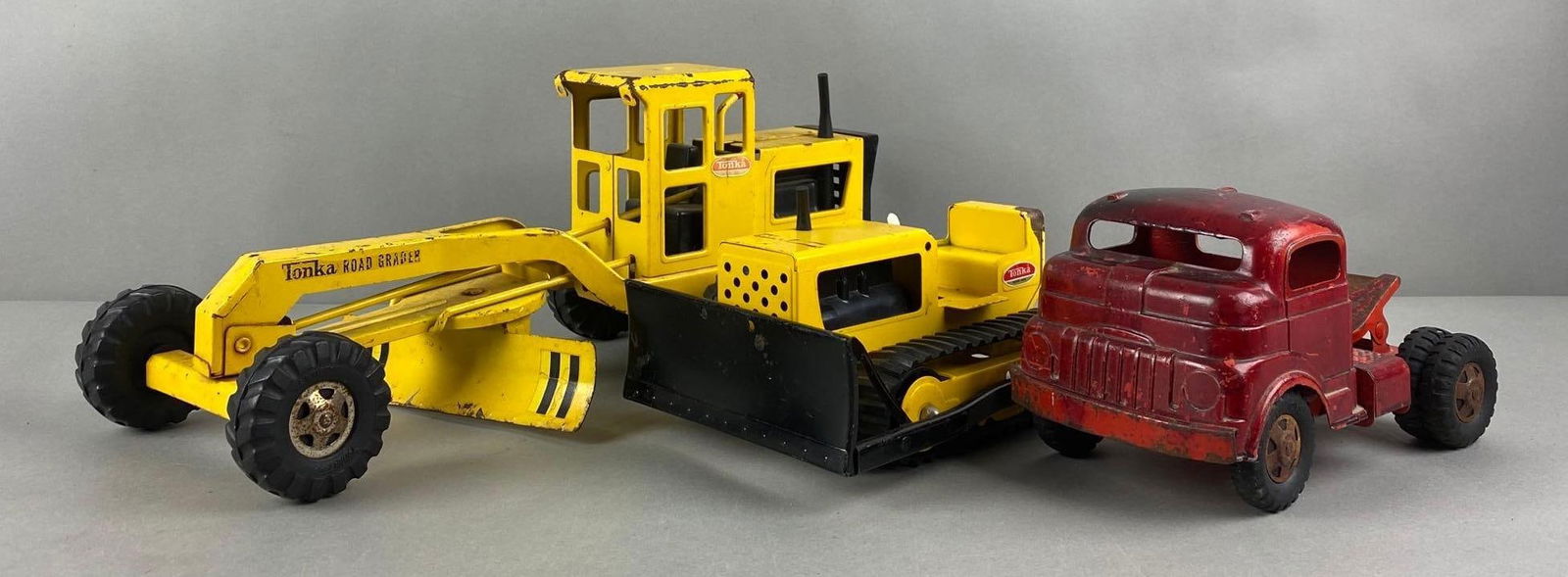 Group of 3 Pressed Steel Vehicles: Includes Tonka Road Grader, Structo Semi Cab, and Tonka Bull Dozer. Largest measures 17 x 6 1/2 x 7 inches.