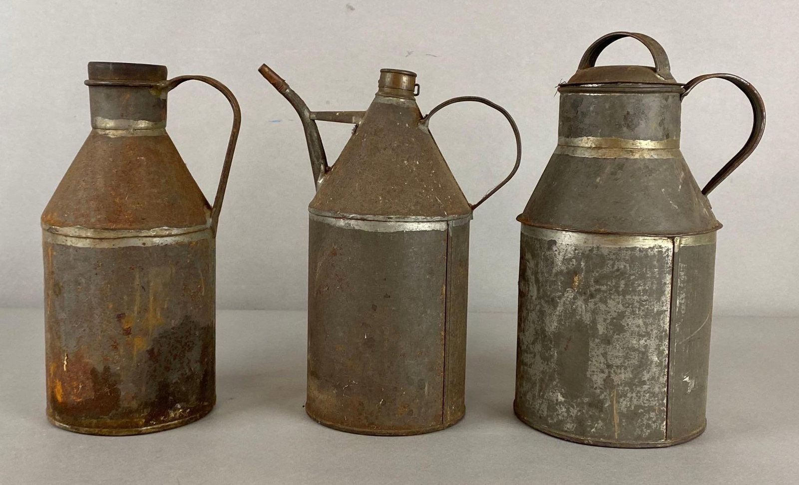 Group of 3 Antique Primitive Tin Canisters: Includes oil can, dairy pail, and oil canister, Some rust throughout, Largest measures 11 x 6 x 5 1/2 inches.